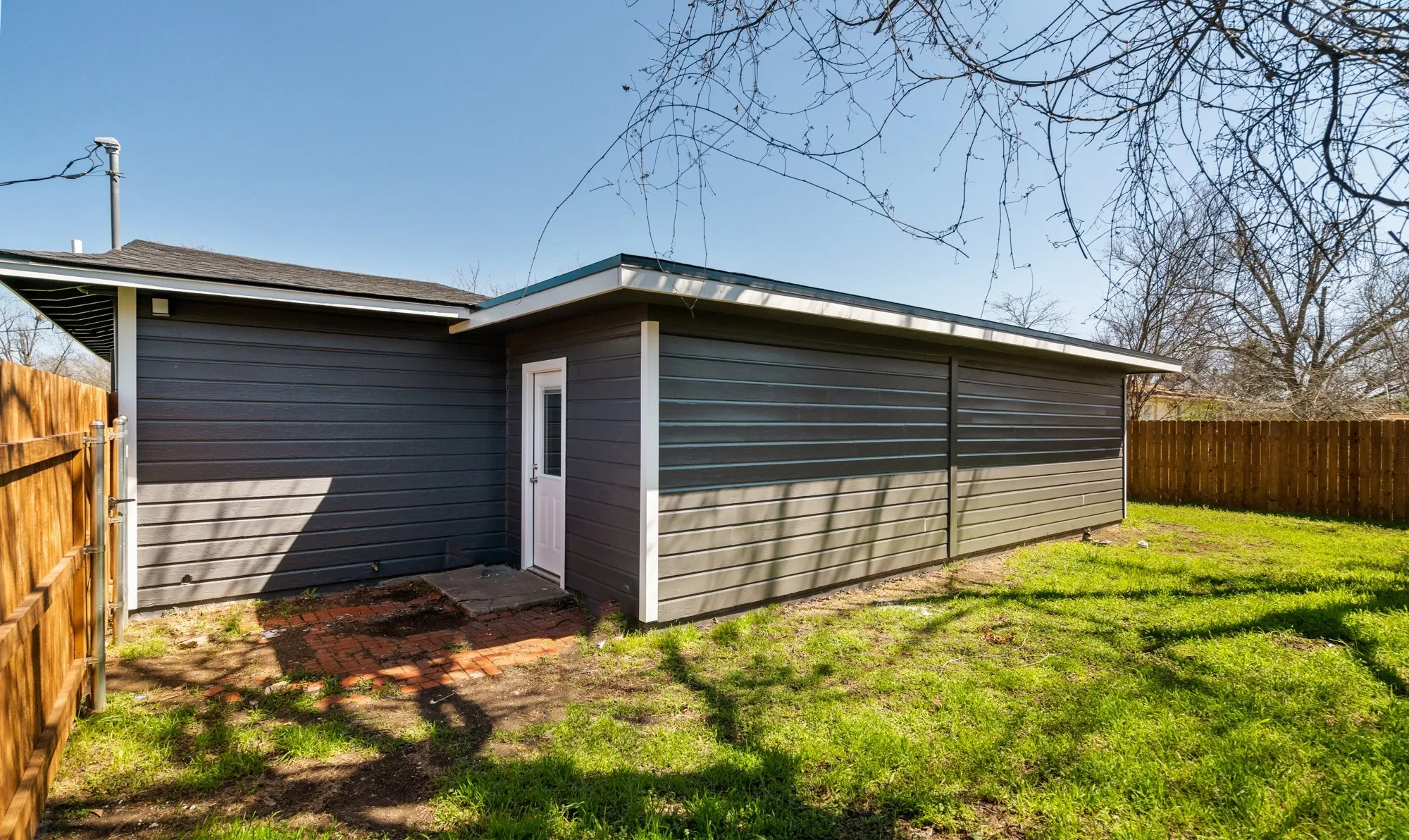 Exterior building with dark gray siding, white trim, and a white single-panel door