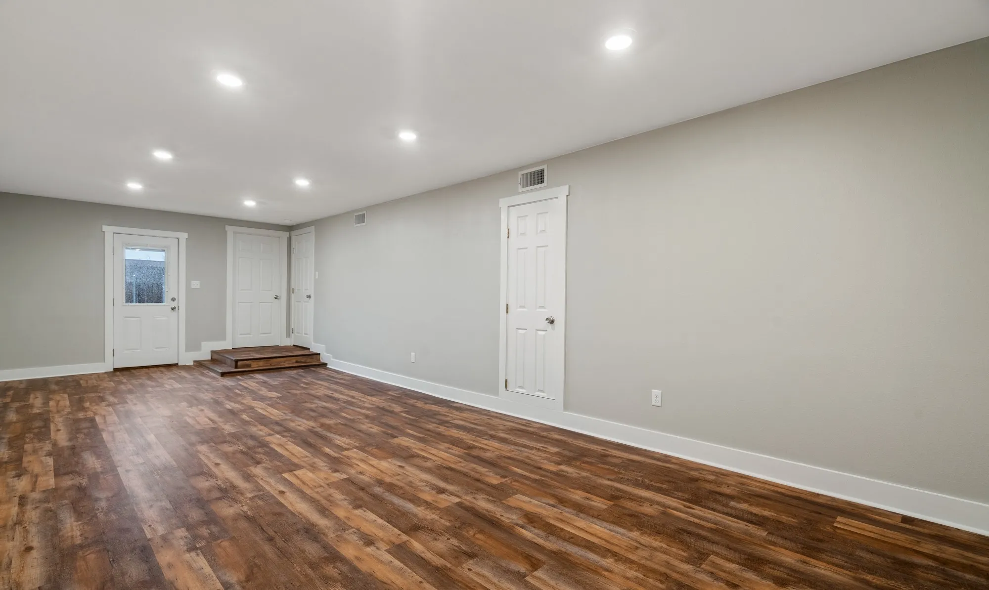 Recessed ceiling lighting, wood-finish flooring, white baseboards, and neutral wall tones