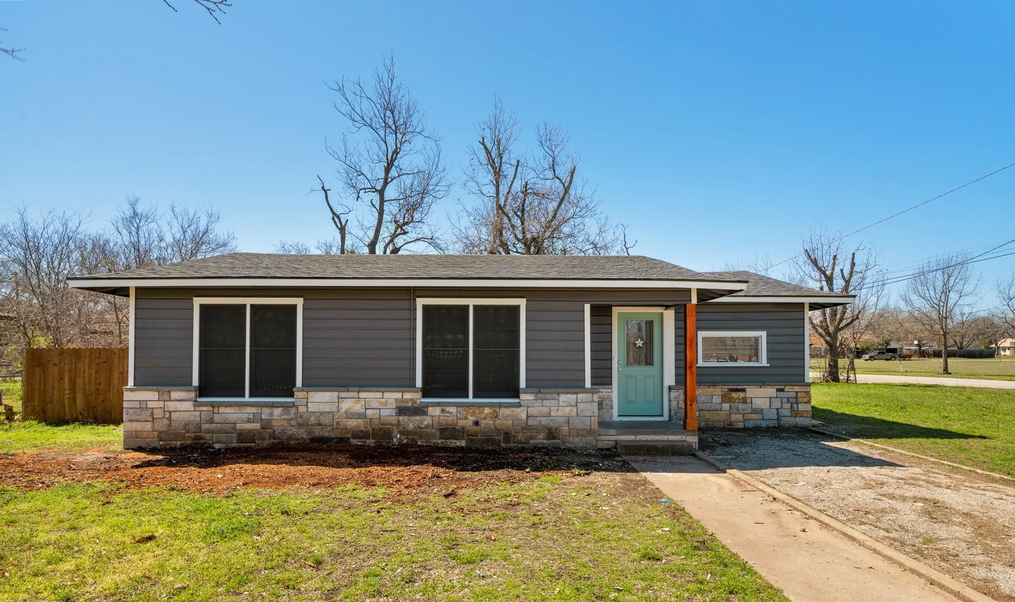 Exterior featuring horizontal siding, stone veneer accents, and a light blue entry door