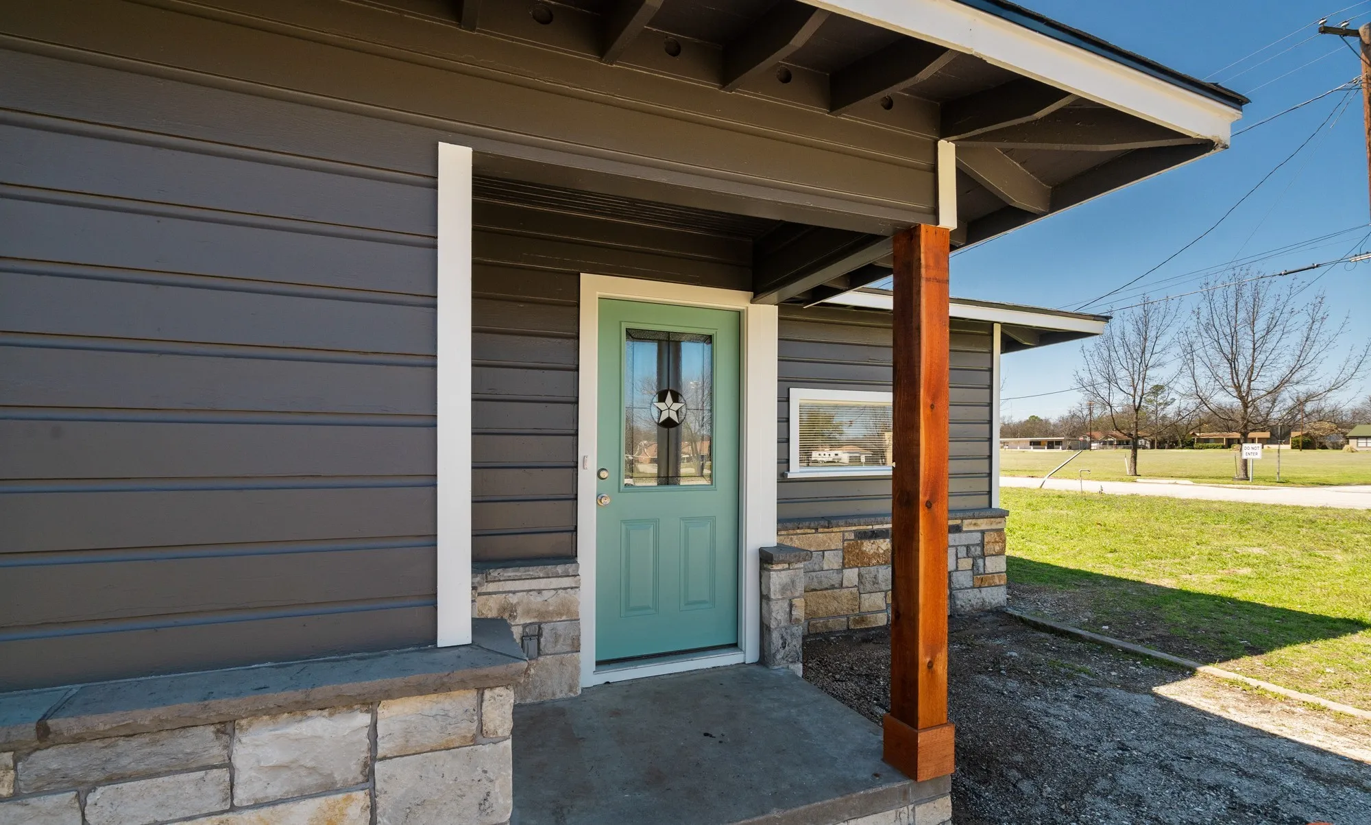 Exterior featuring horizontal siding, a covered entry, a wood support post, and stone accents