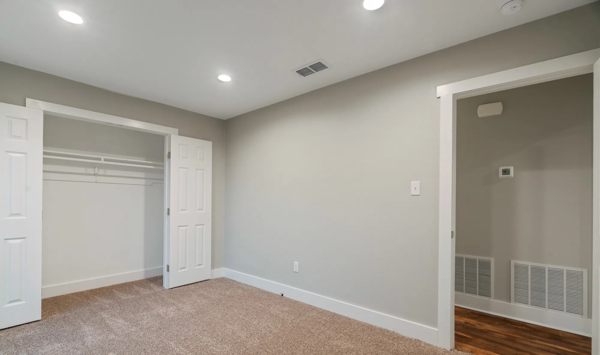 Plush carpet flooring, recessed ceiling lighting, a built-in closet with shelving and hanging rods, and a white trim entry