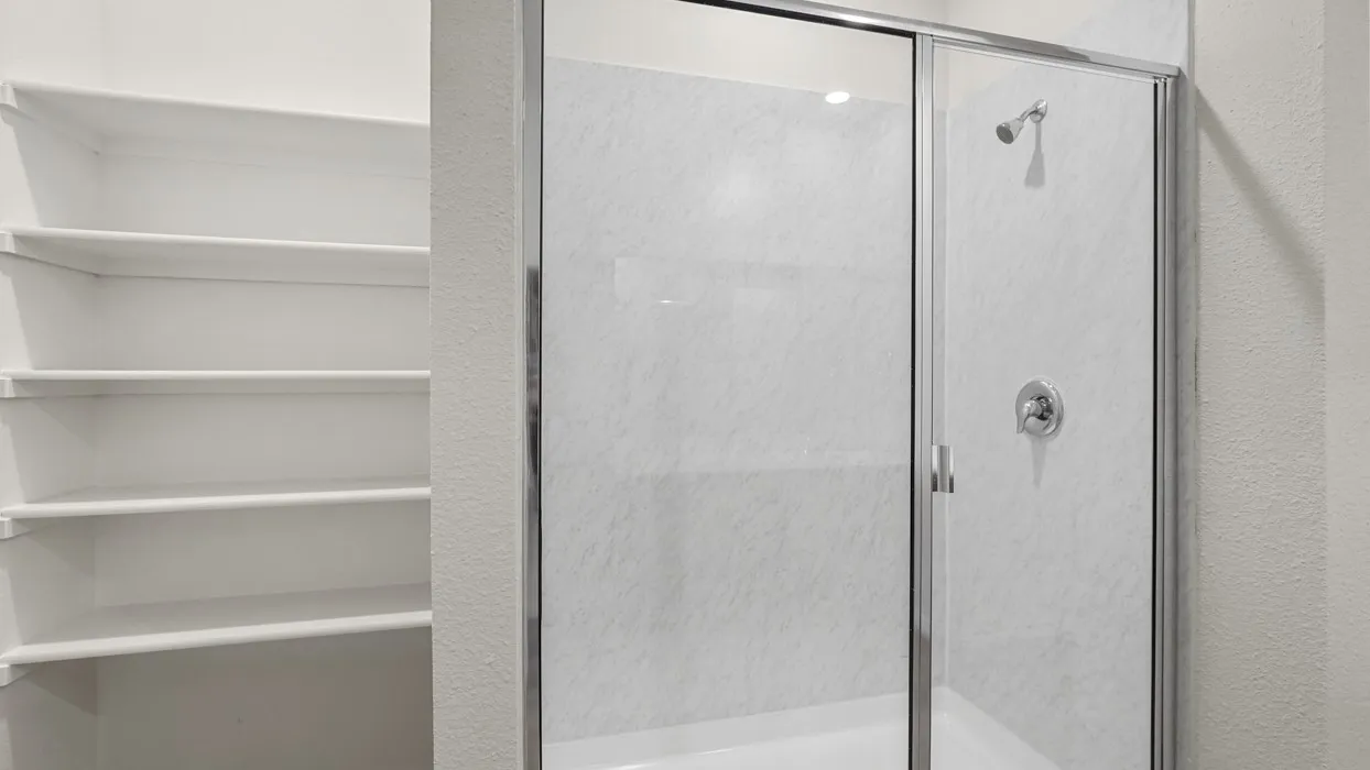 Walk-in shower with clear glass enclosure and chrome fixtures