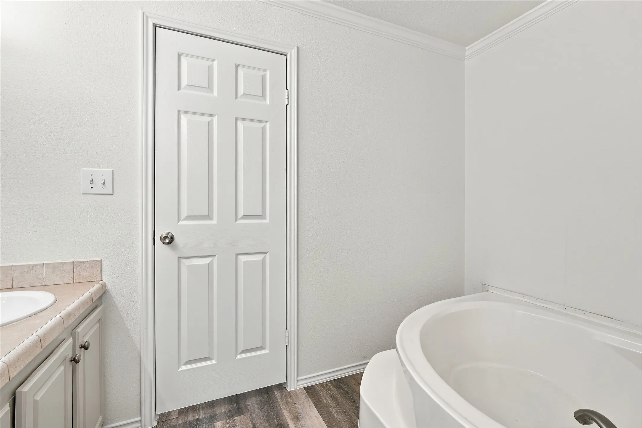 Soaking tub, wood-look flooring, and crown molding