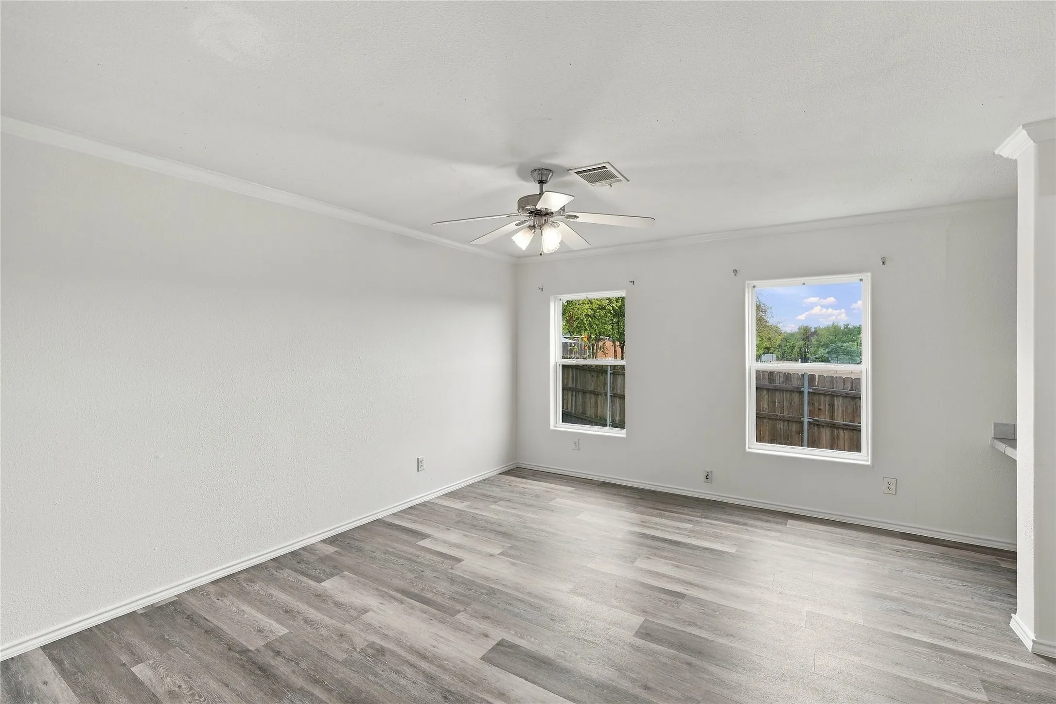 Wood-look flooring with white baseboards and crown molding