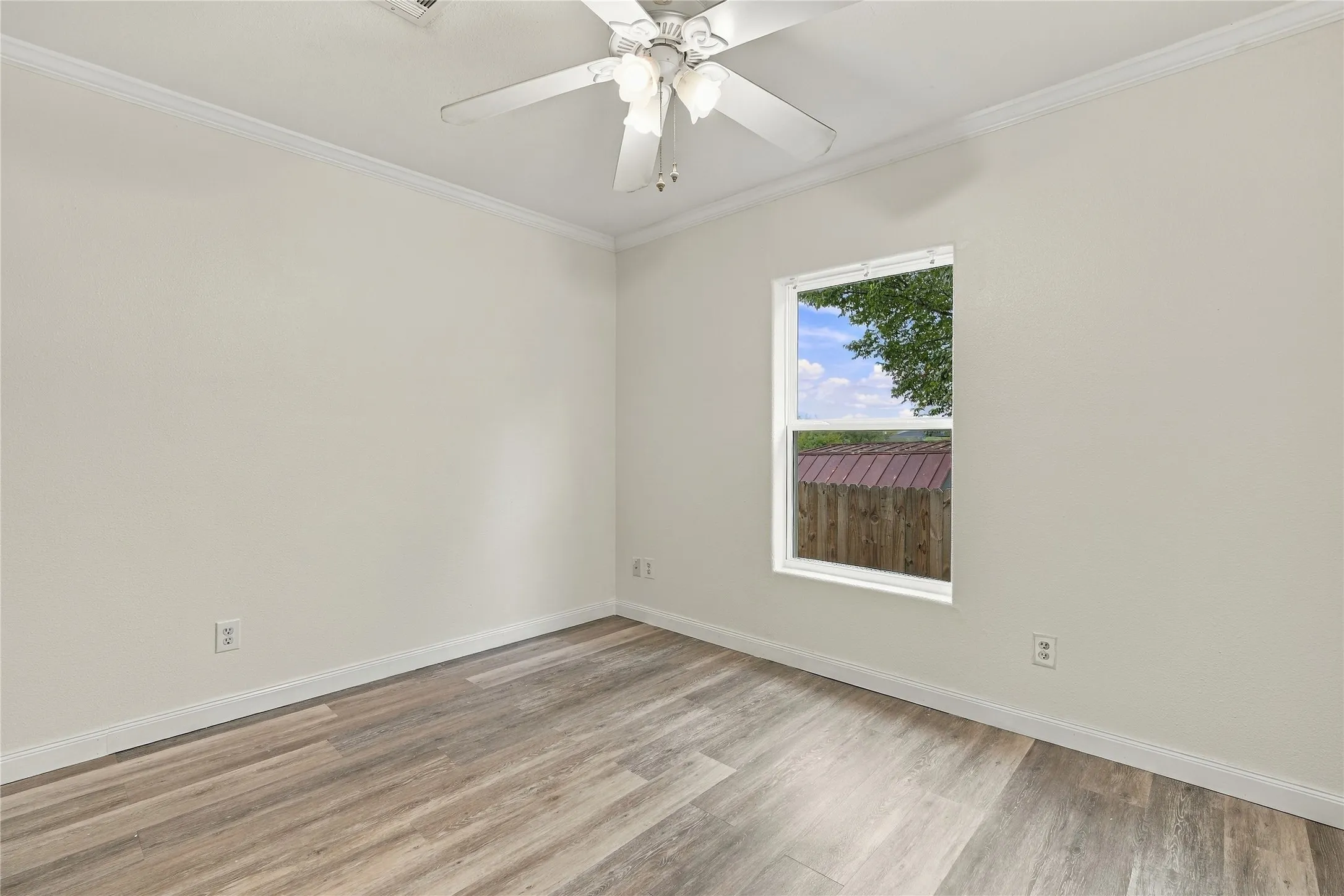 Wood-look flooring with white baseboards, crown molding, and a ceiling fan