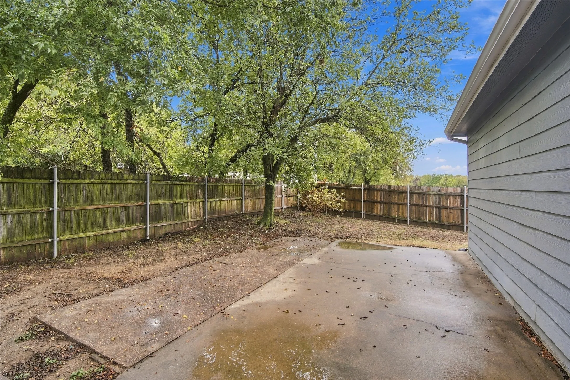 Fenced perimeter, mature tree, concrete patio area,  and rain gutters