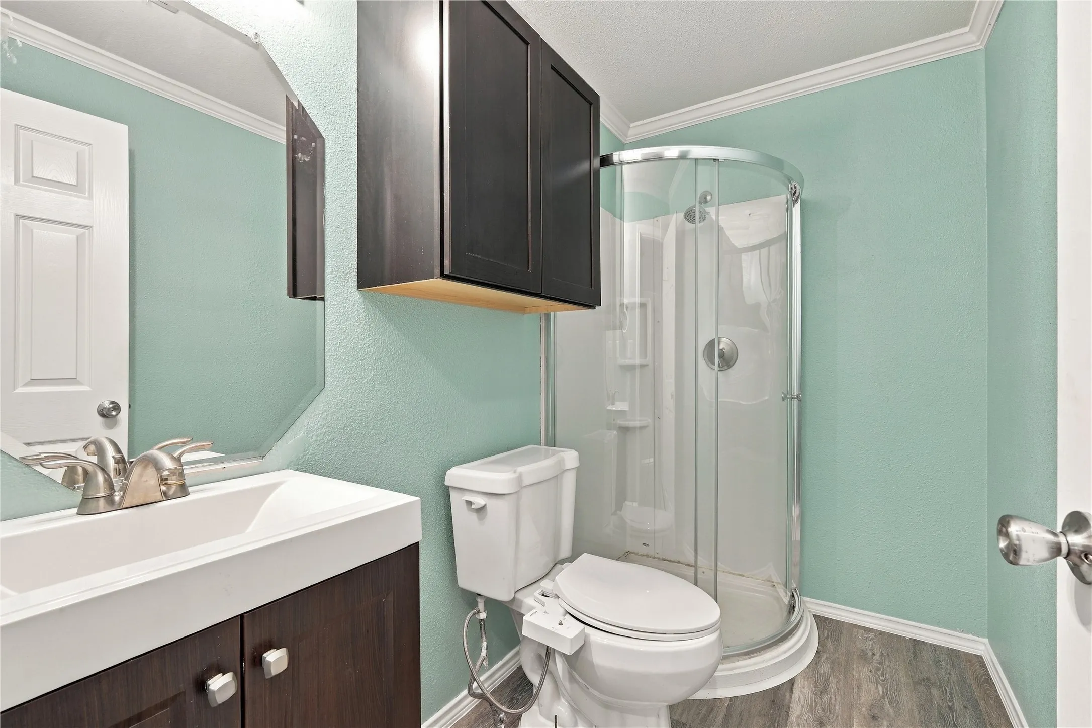Dark wood-finish vanity with an integrated white sink, brushed nickel faucet, and beveled mirror