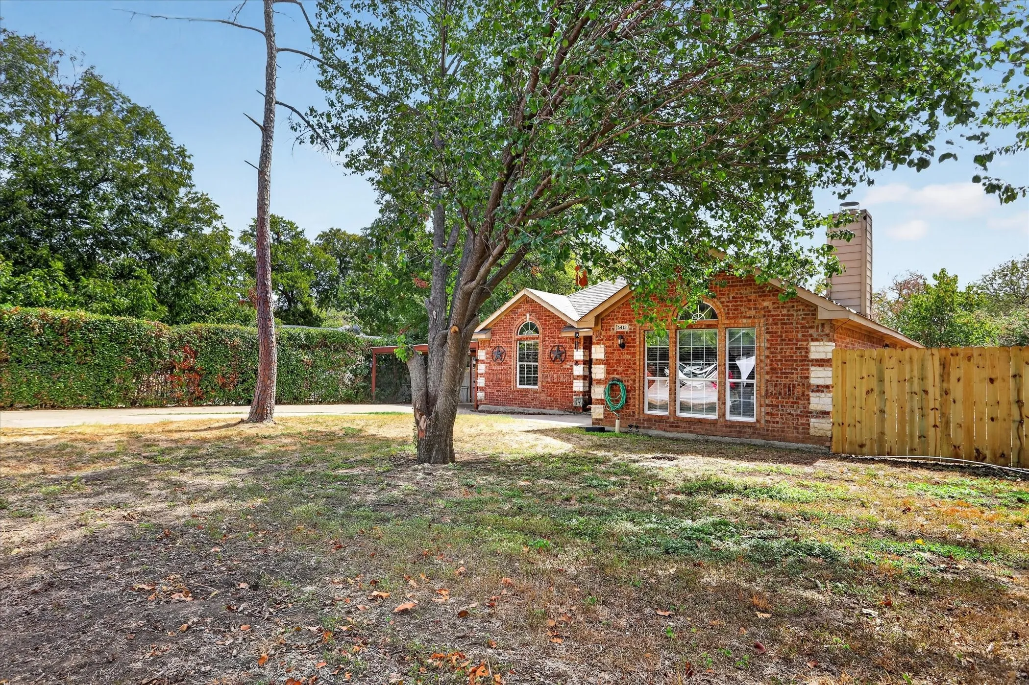 Brick exterior with arched windows, a prominent chimney, and a wooden privacy fence