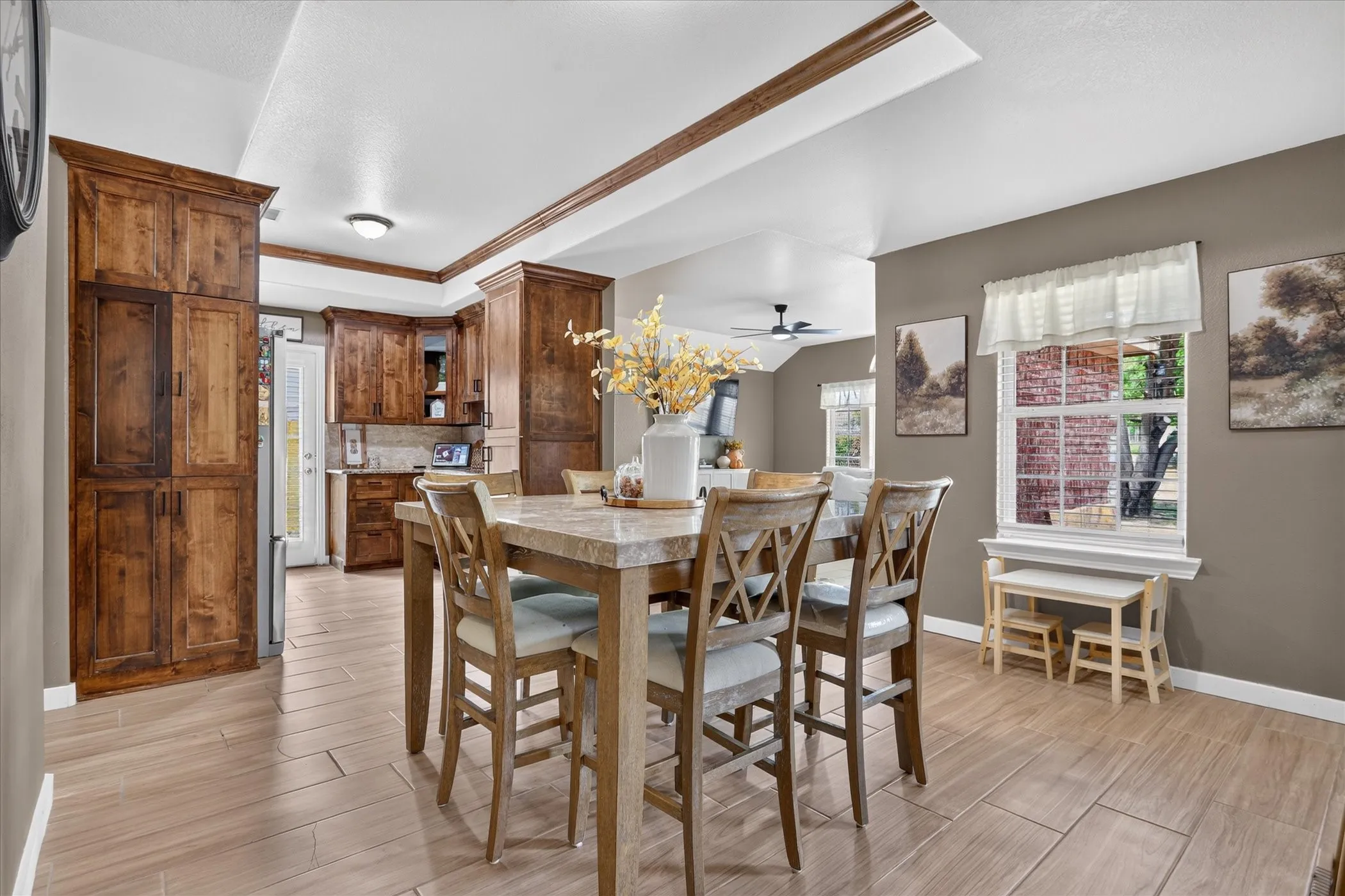 Warm wood-finish cabinetry, light wood-finish flooring, recessed ceiling lighting, and a kitchen pass-through