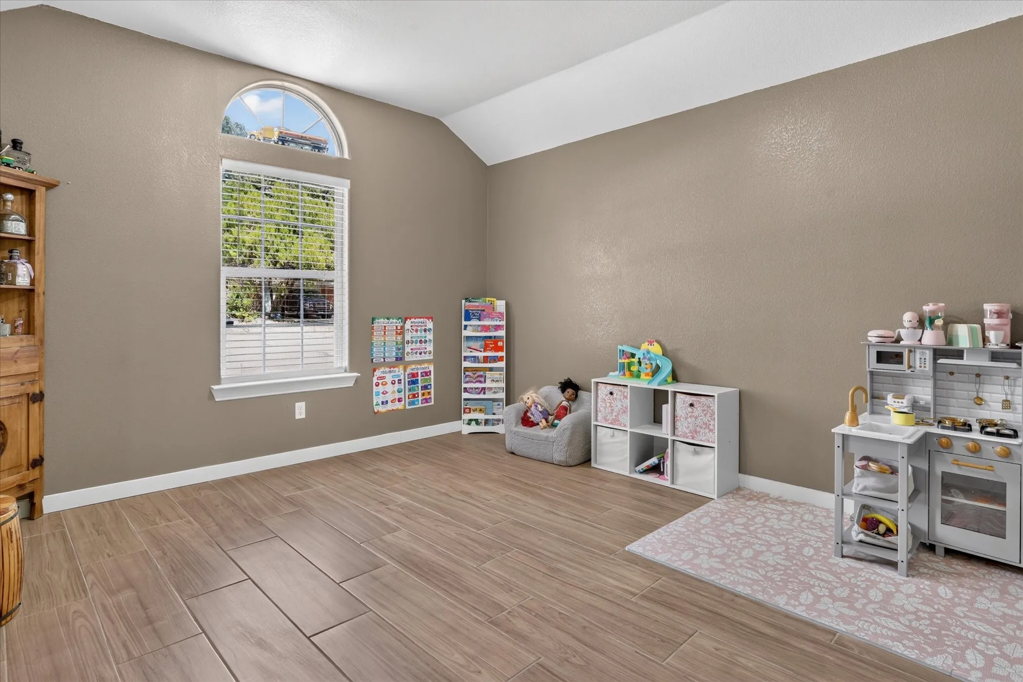 Vaulted ceiling with a half-round transom window, wood-finish flooring, and crisp white trim details