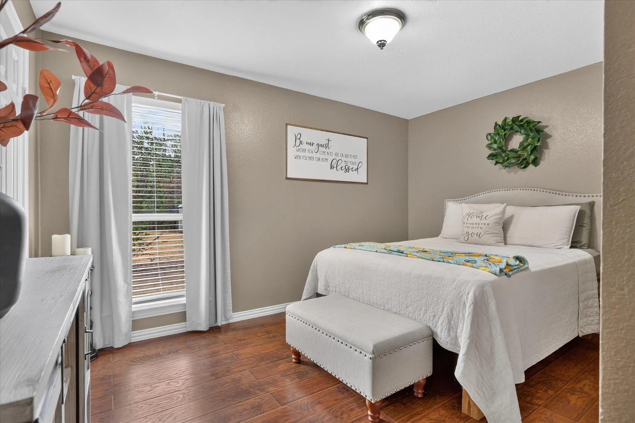 Wood-finish flooring, single window with blinds, recessed lighting fixture, upholstered headboard with nailhead trim