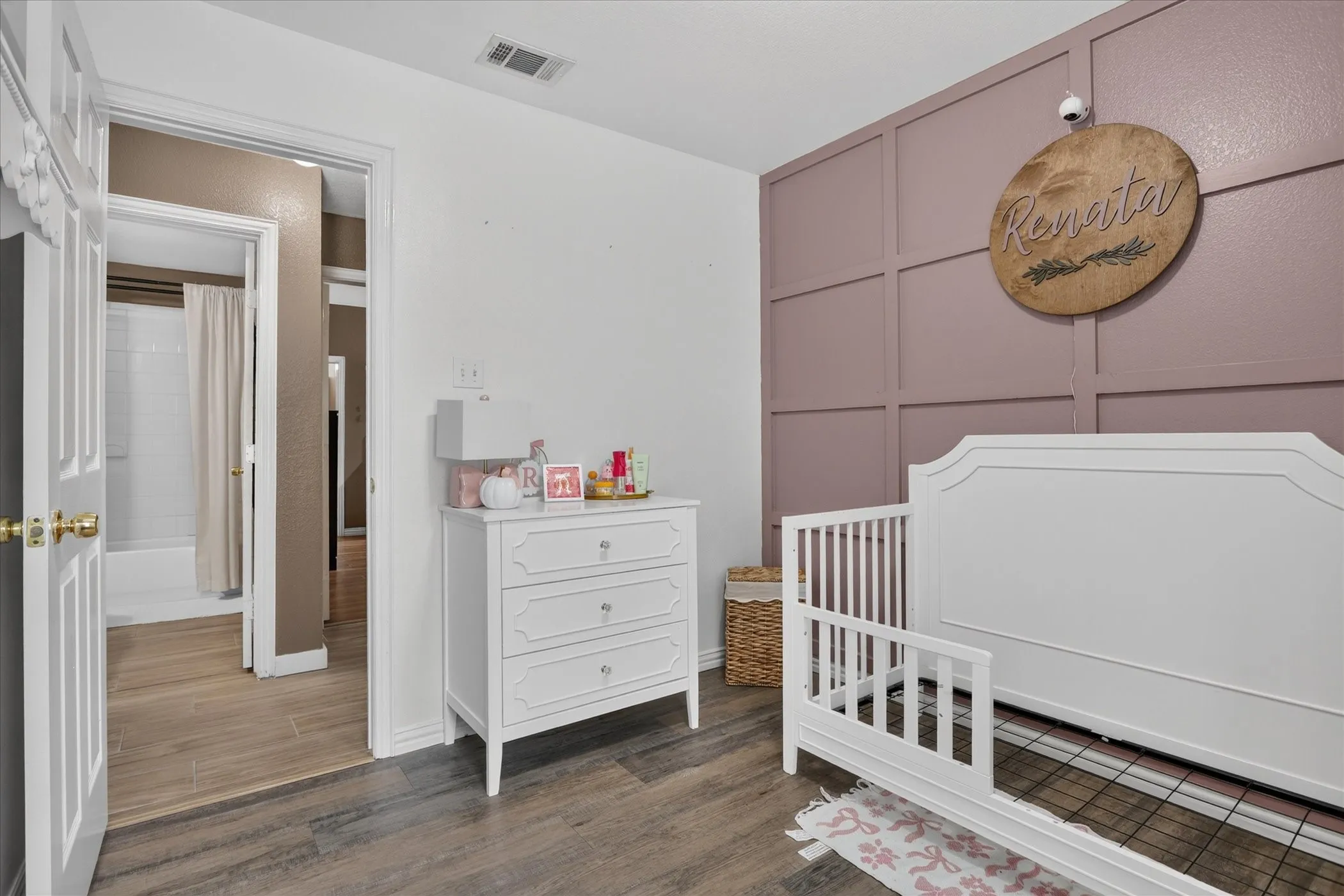 Wood-finish flooring throughout, with a feature wall showcasing wainscoting and painted paneling