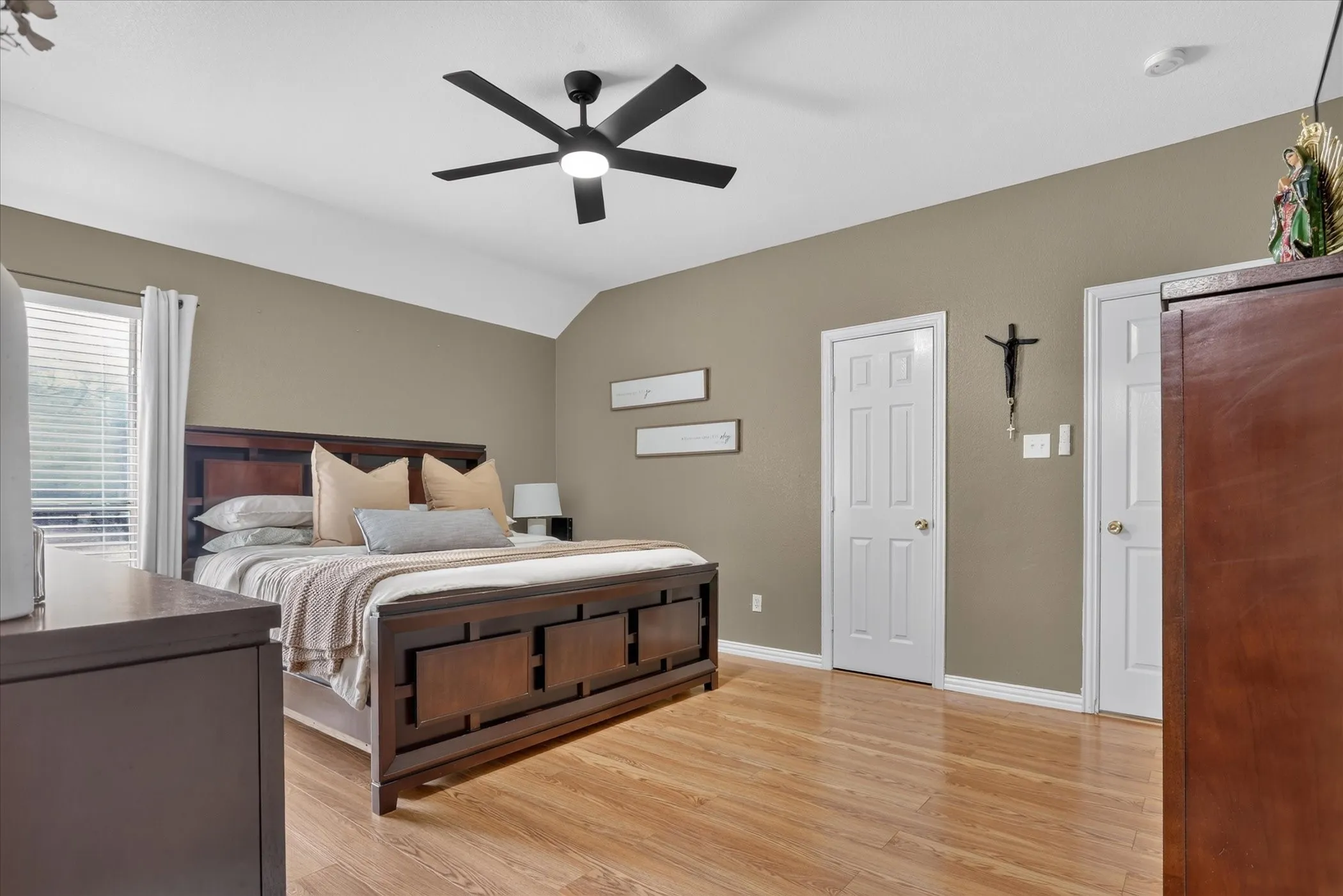 Wood-finish flooring with a modern ceiling fan, white paneled doors, and a window with blinds