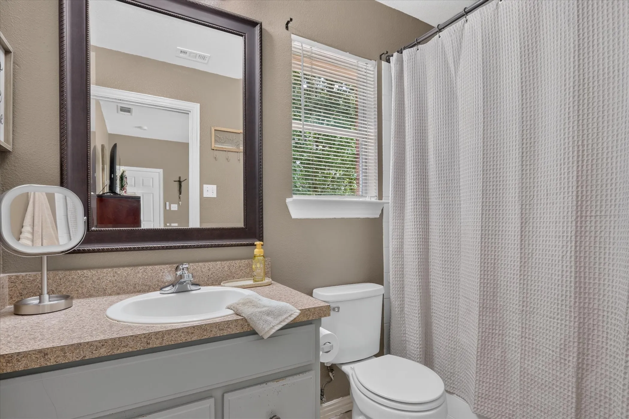 Vanity with integrated sink, chrome faucet, and a large framed mirror