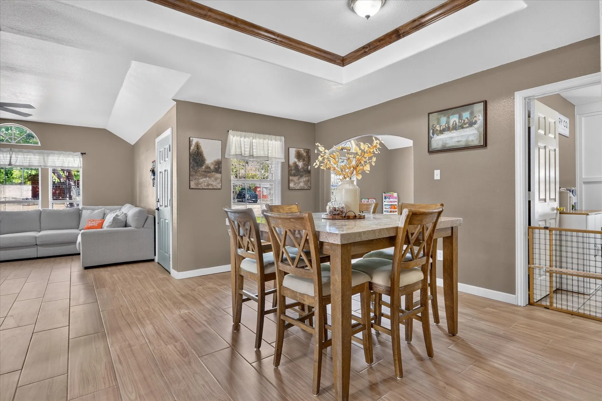 Tray ceiling with wood-finish trim, wood-look tile flooring, arched doorway, and recessed lighting fixture