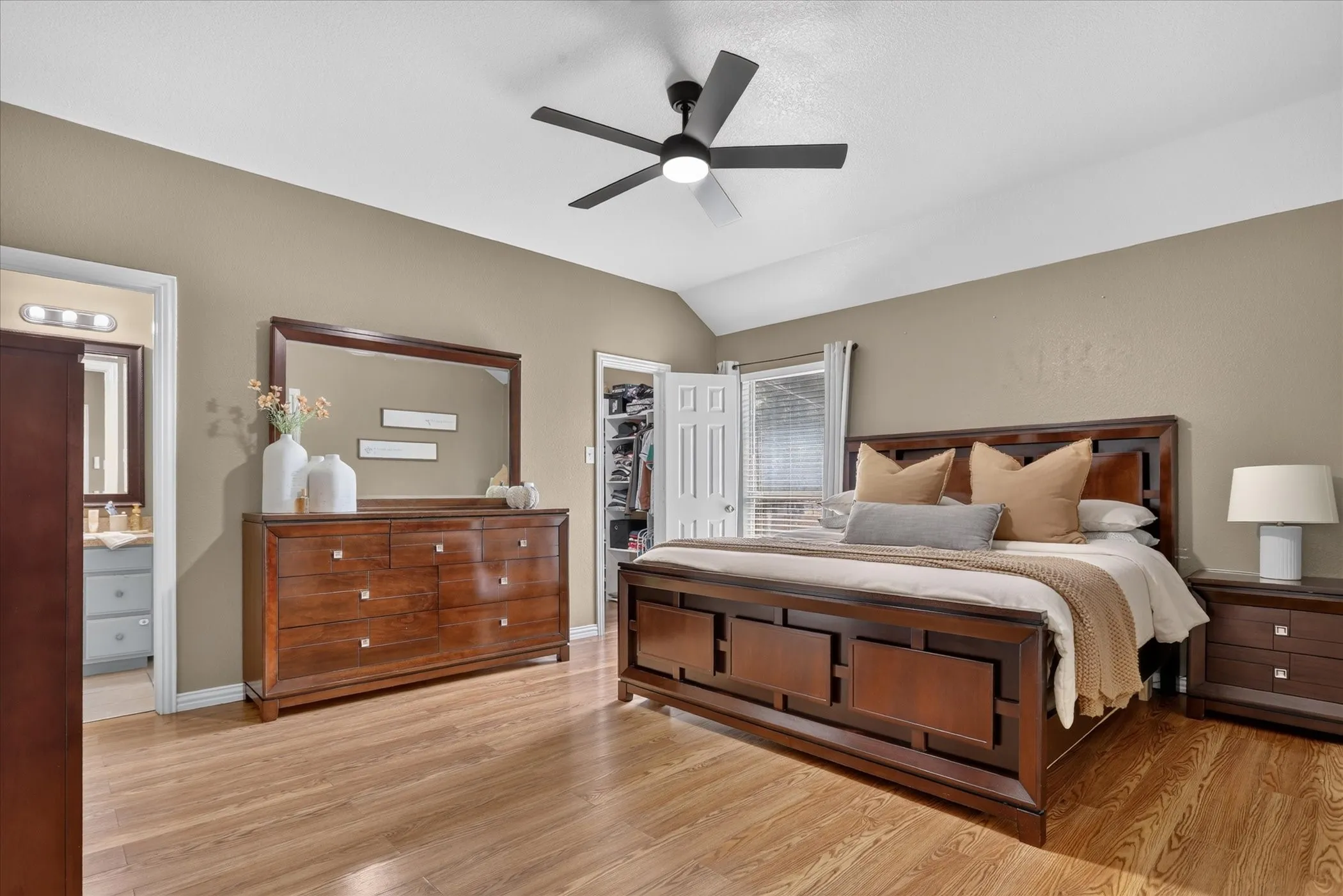 Vaulted ceiling, wood-finish flooring, ceiling fan, and window with blinds
