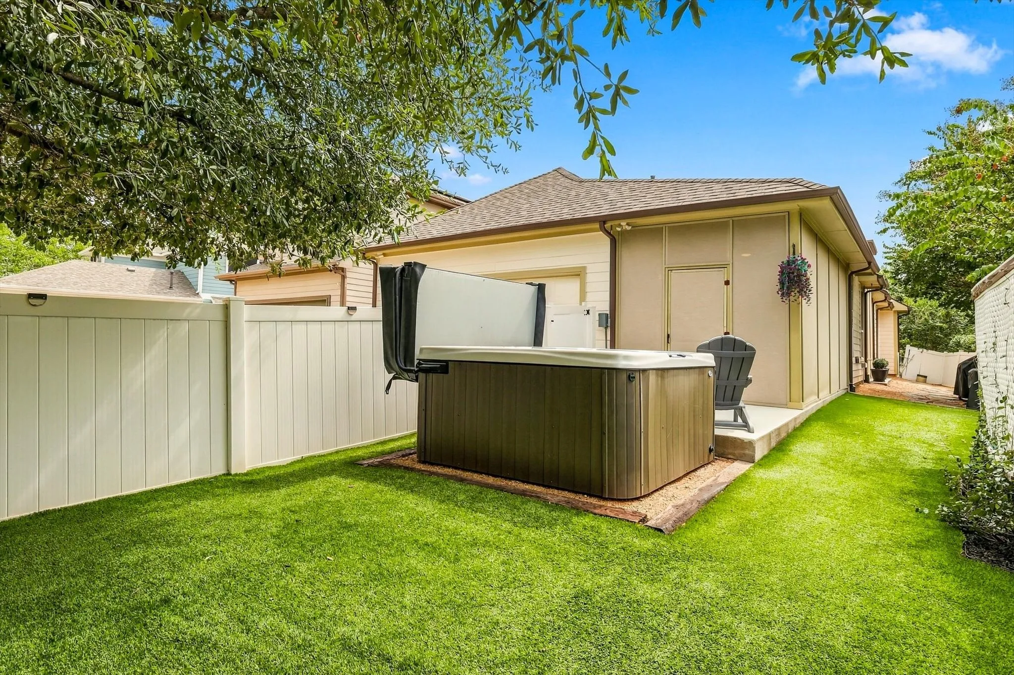 Turf and privacy fencing create a tidy outdoor setting around the hot tub and rear-entry garage.