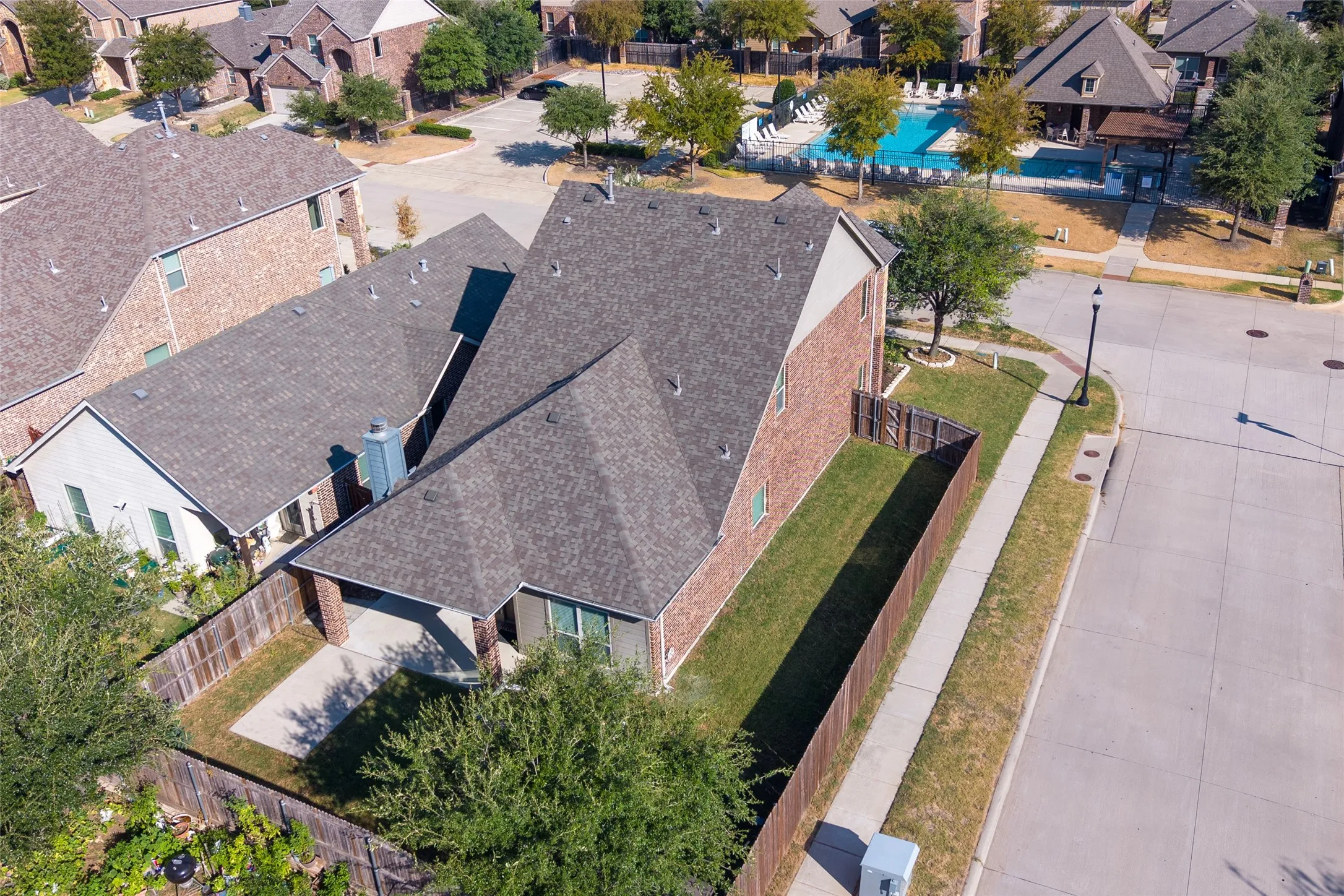 Brick exterior, fenced yard, paved driveway, concrete sidewalk, shingle roofing