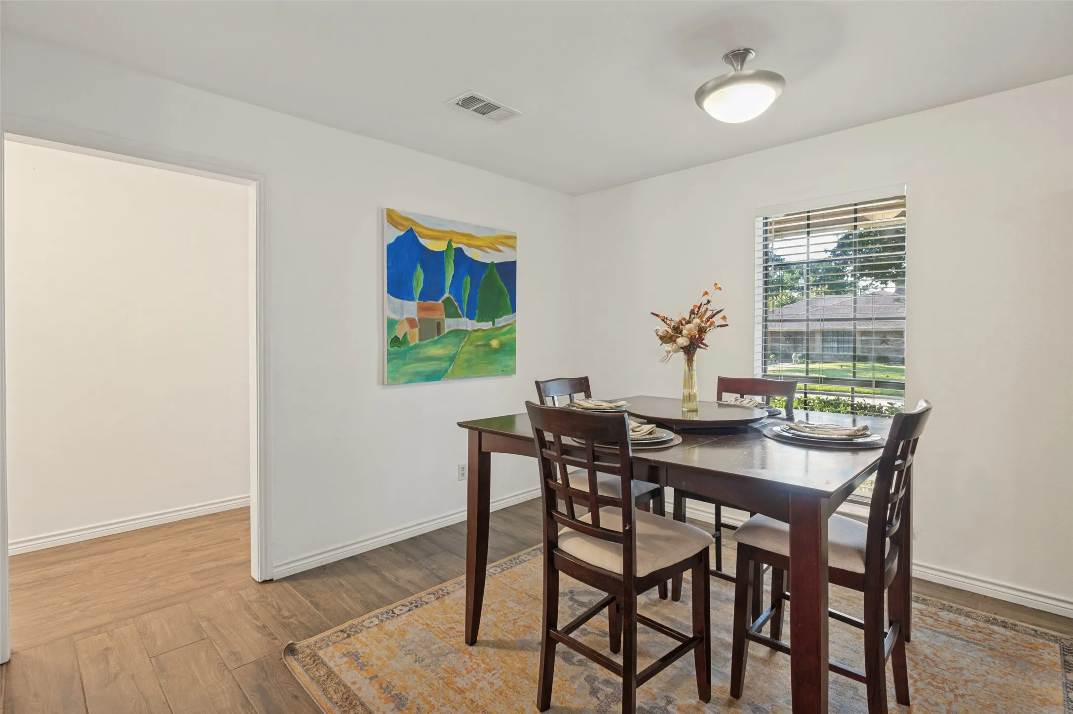 Neutral wall paint, wood-finish flooring, and a single window with horizontal blinds