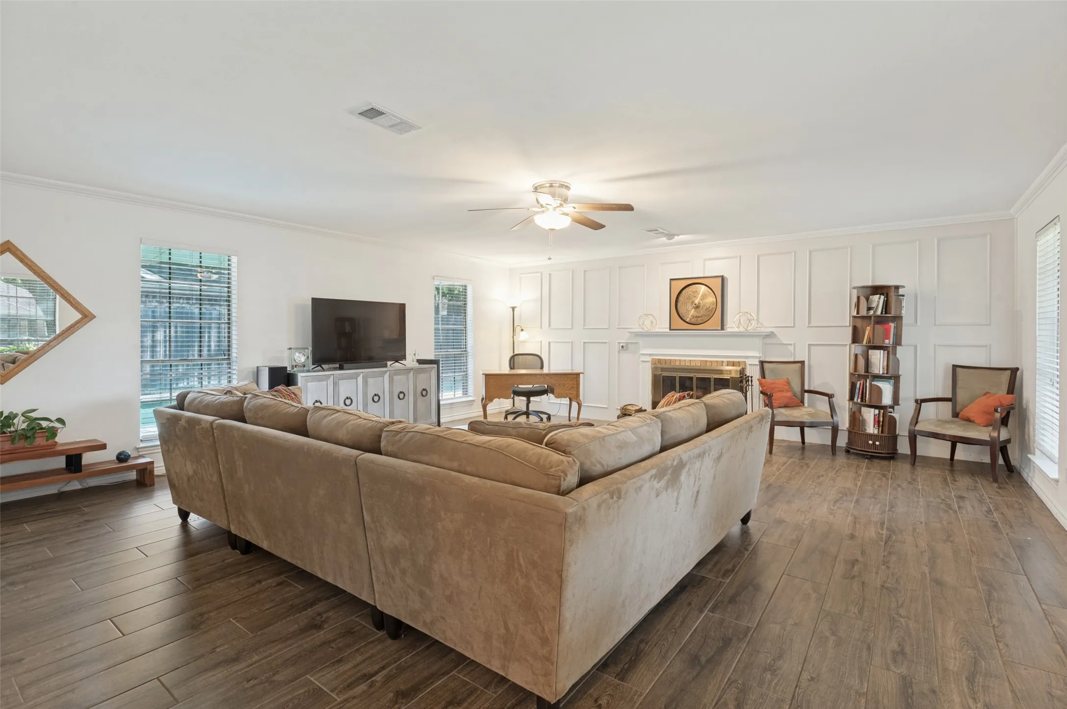 Wood-finish flooring, white walls, multiple windows with blinds, recessed lighting, and a ceiling fan