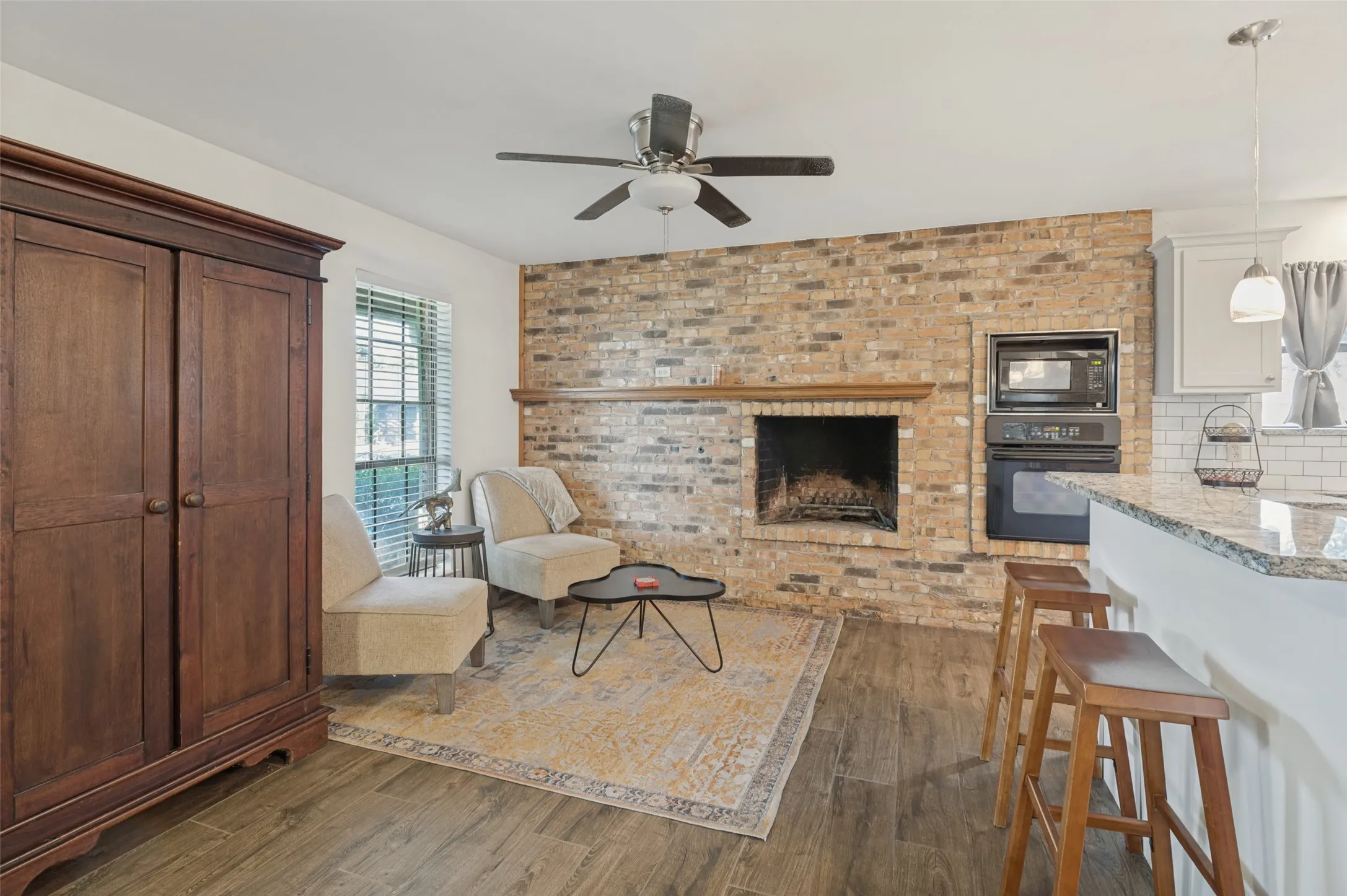 Brick accent wall featuring a fireplace and wood mantel