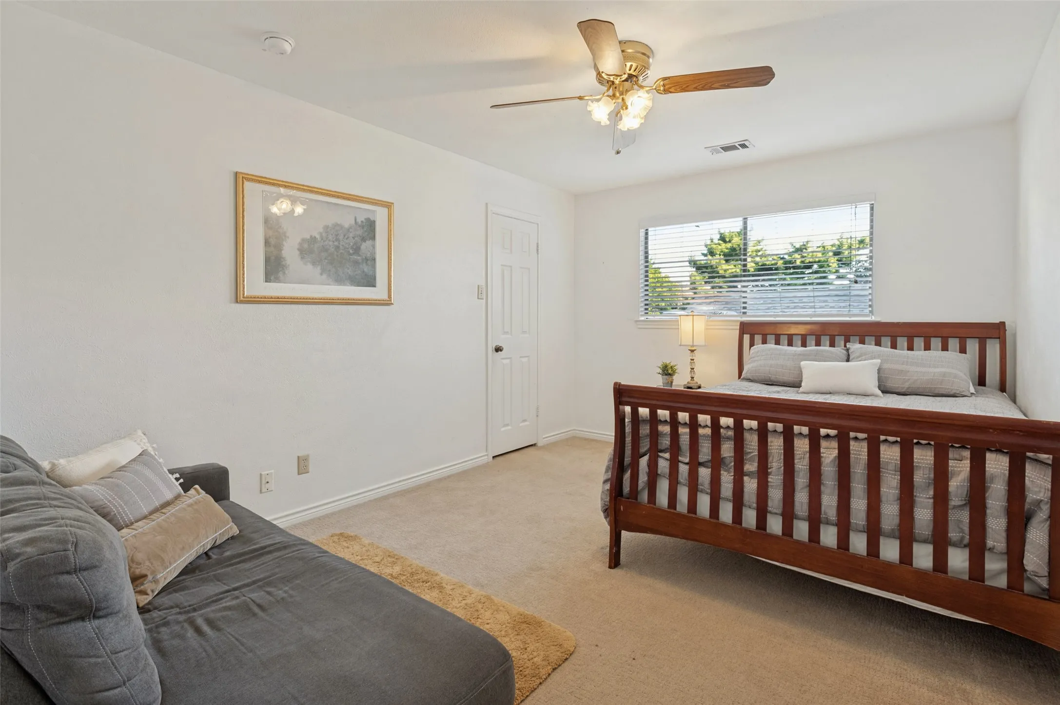 Carpeted flooring with a contrasting baseboard, ceiling fan with integrated lighting, and a window with horizontal blinds