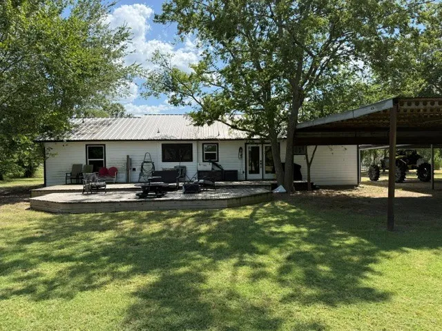Expansive back deck, mature trees, metal roof, carport, and double doors