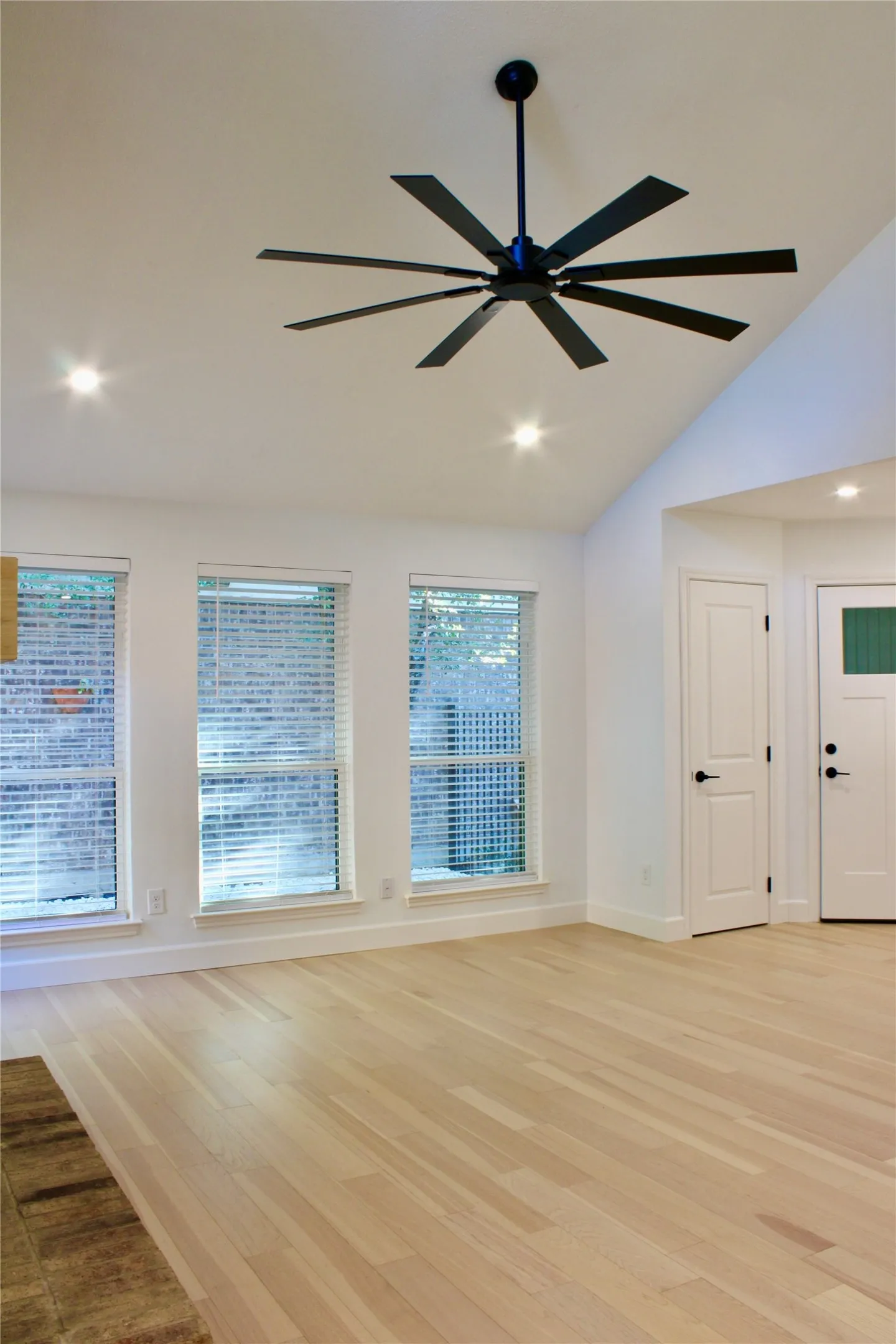 Vaulted ceiling featuring a multi-blade ceiling fan, recessed lighting, and wood-finish flooring