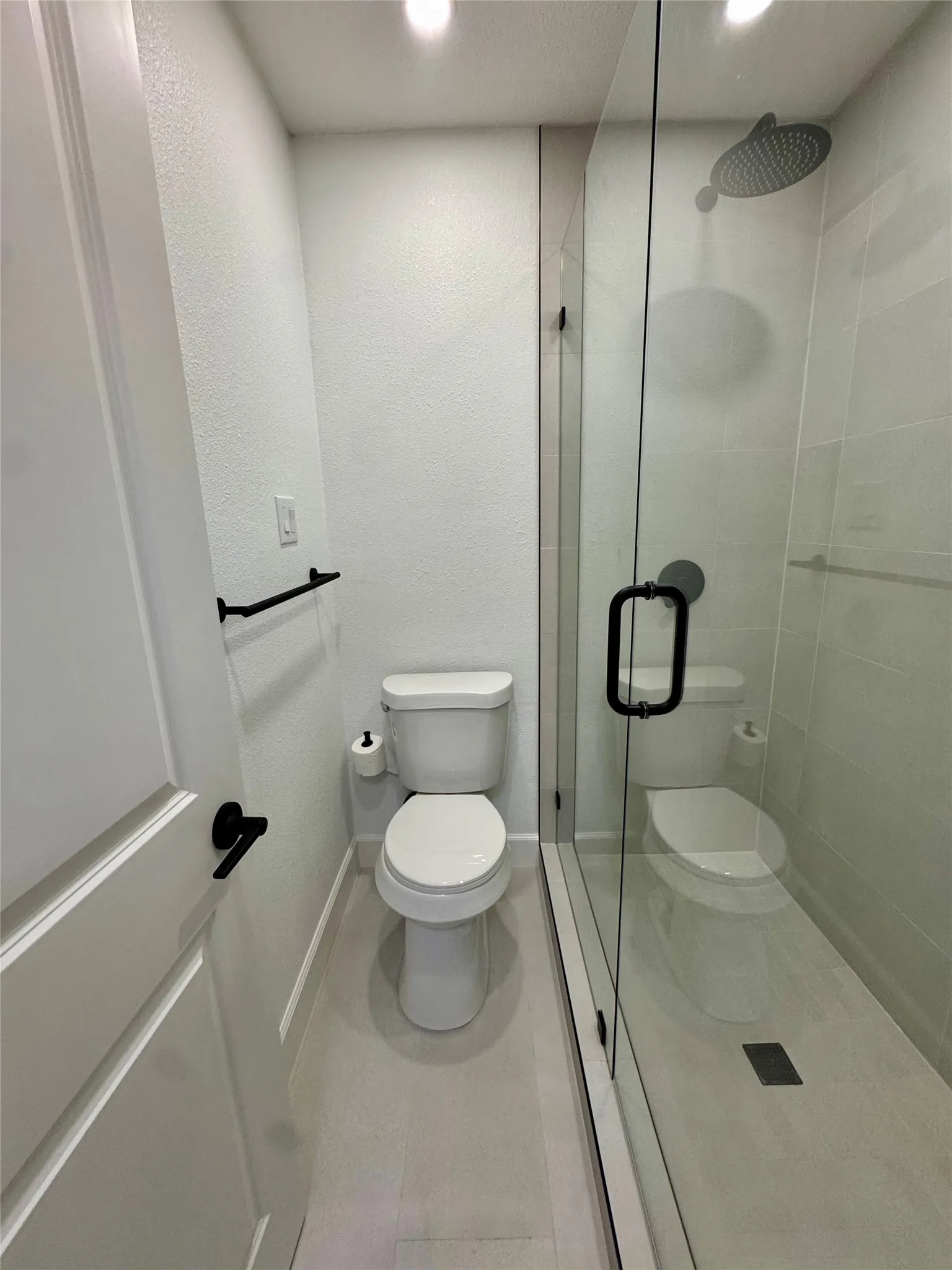Modern bathroom featuring a frameless glass shower enclosure, rain shower head, and matte black fixtures