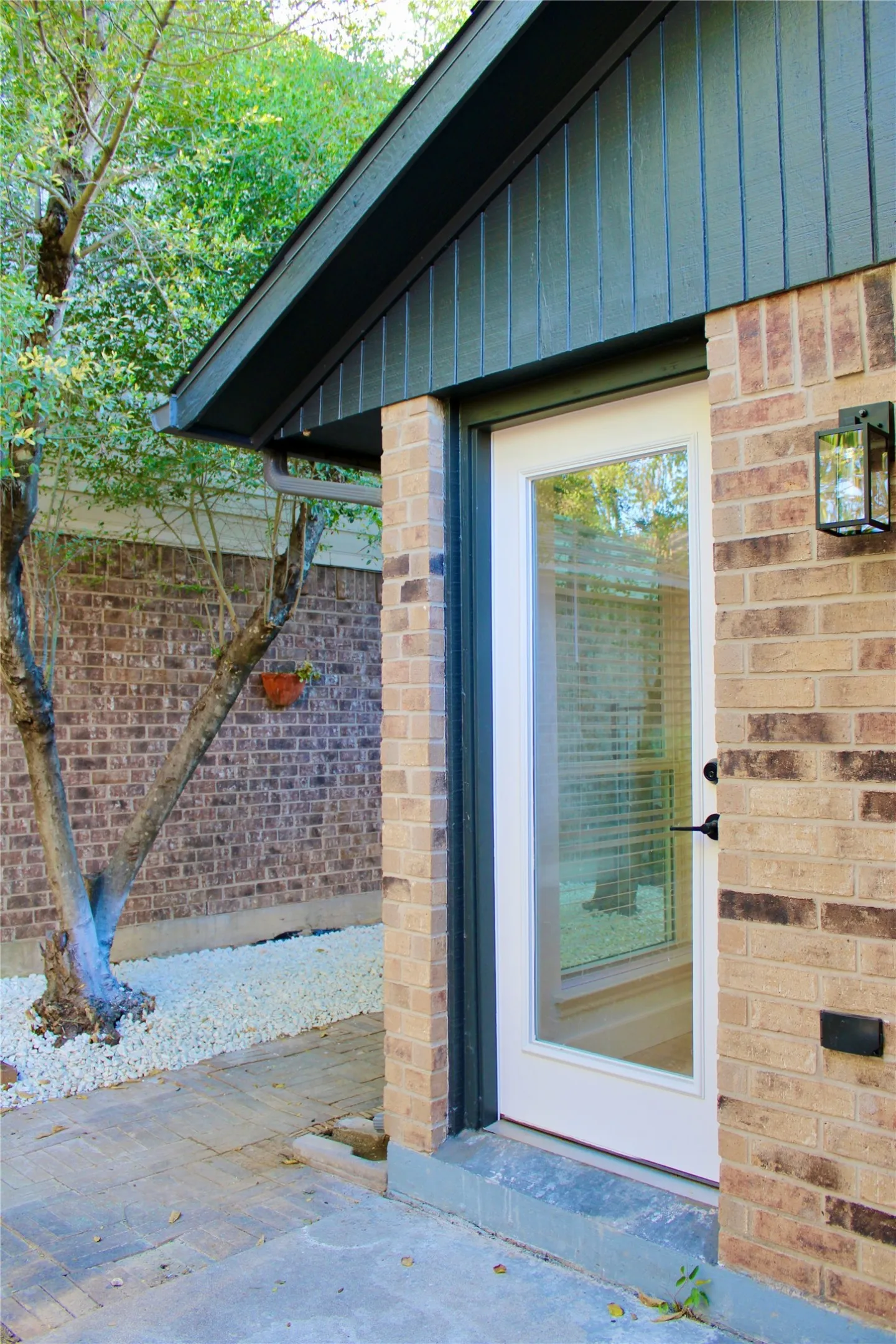 Brick exterior with board and batten siding, outdoor lantern-style lighting, and a full-light door
