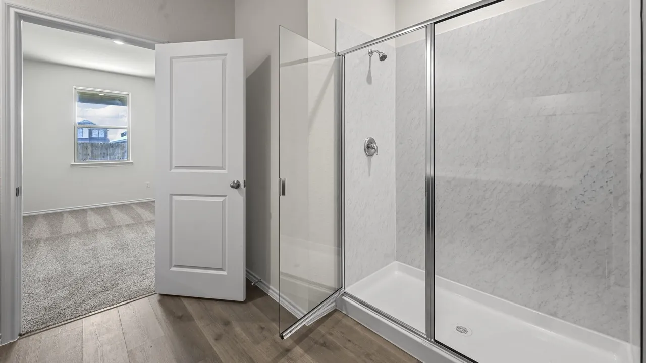 Walk-in shower with clear glass enclosure and tile-look wall panels