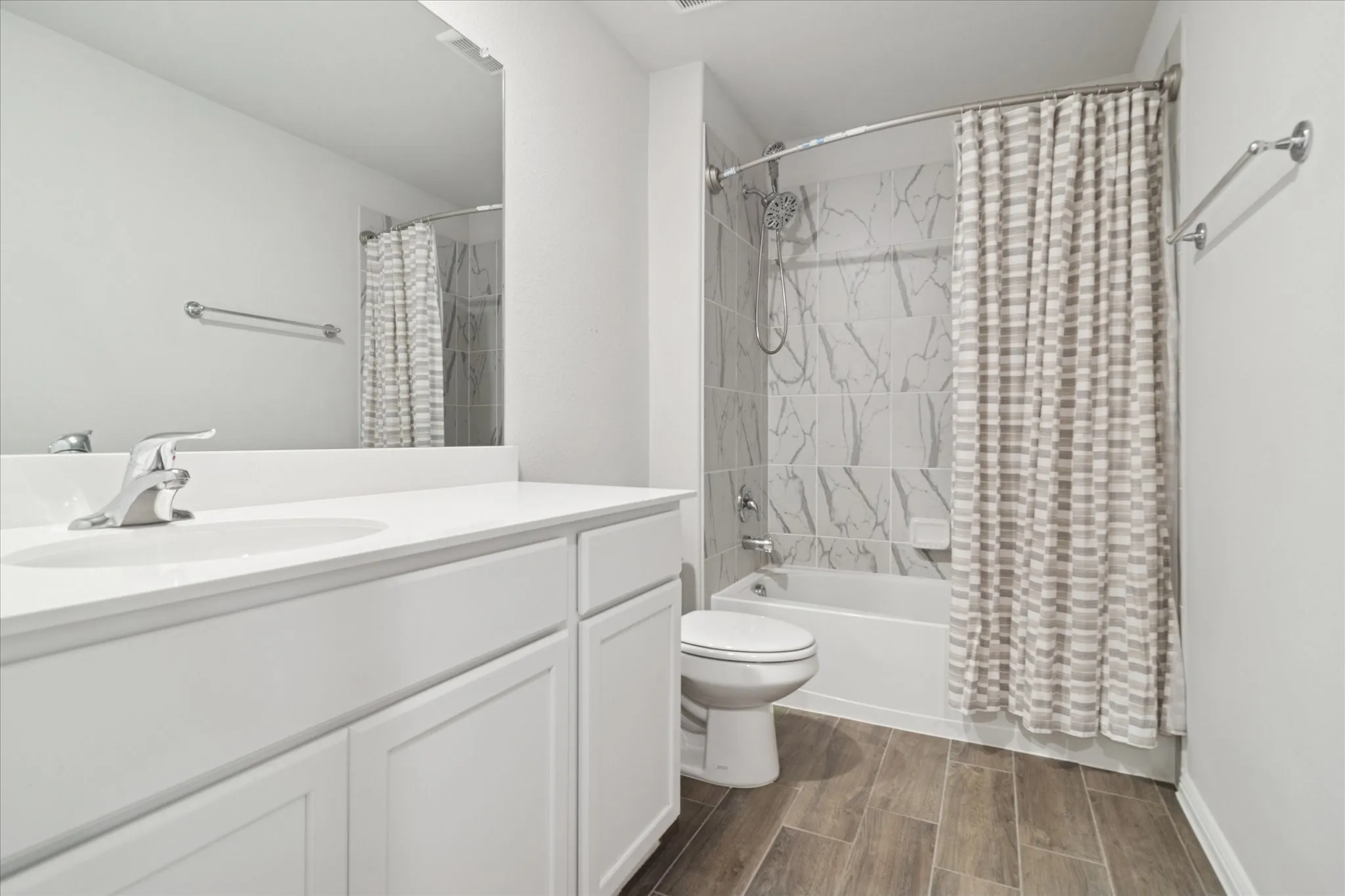 White vanity with an integrated sink, polished chrome faucet, full-width mirror, and wood-finish flooring