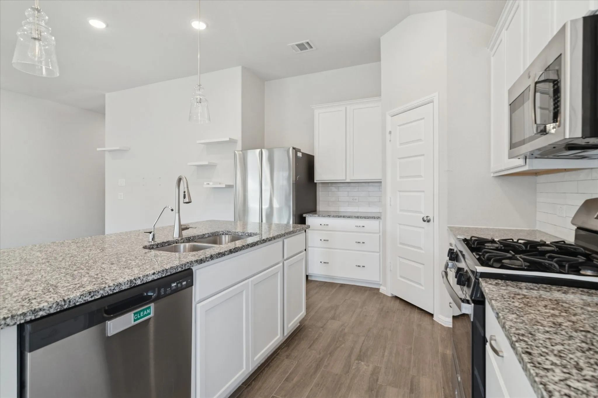 Kitchen featuring white cabinetry, granite countertops, stainless steel appliances, a subway tile backsplash, and wood-finish flooring