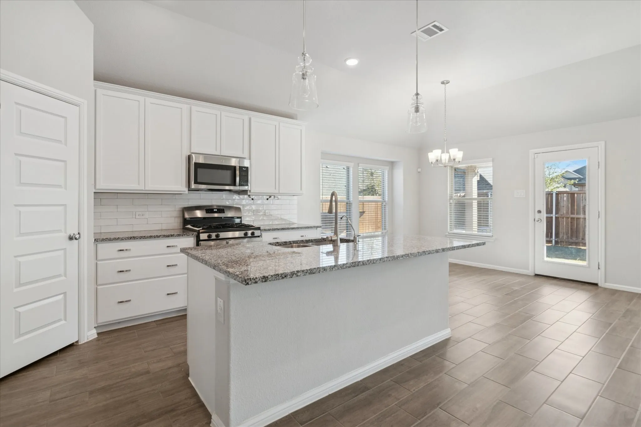 White cabinetry with stainless steel appliances, granite countertops, and subway tile backsplash