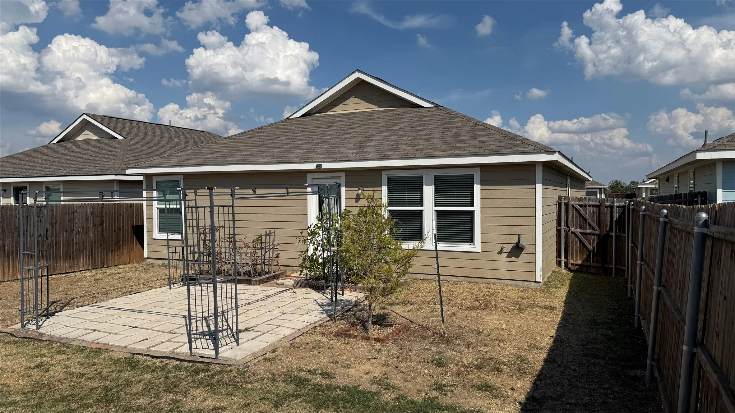 Outdoor patio featuring paver stones, fenced yard, and exterior siding