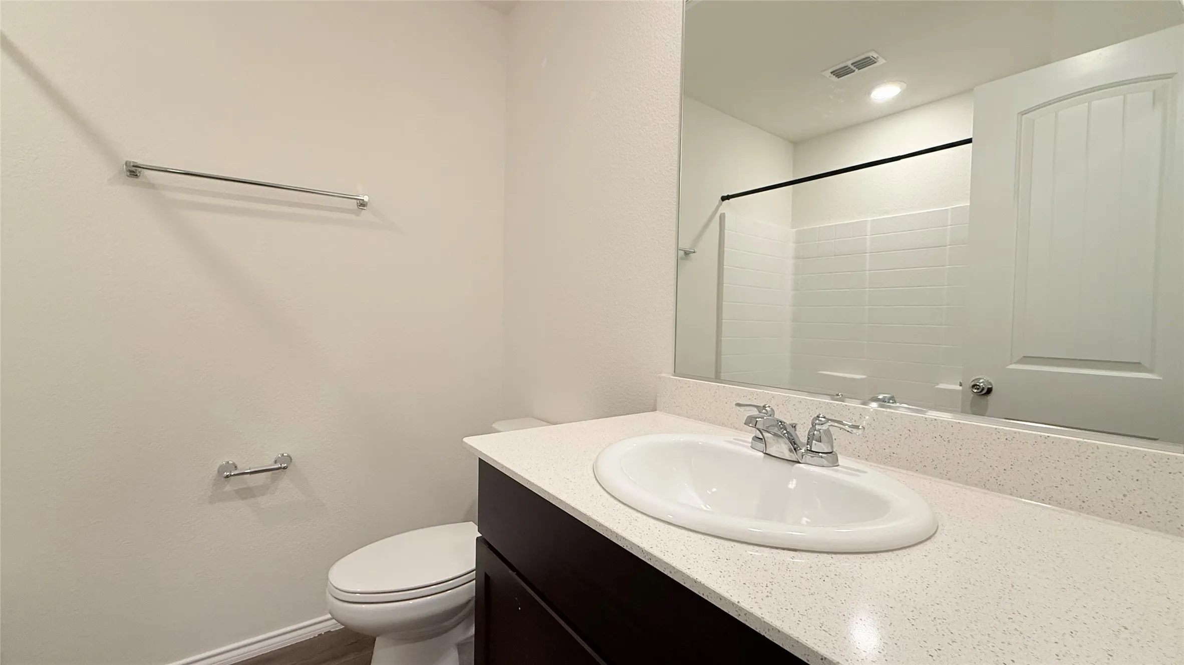 Built-in dark wood-finish vanity with an integrated sink, chrome faucet, and expansive countertop