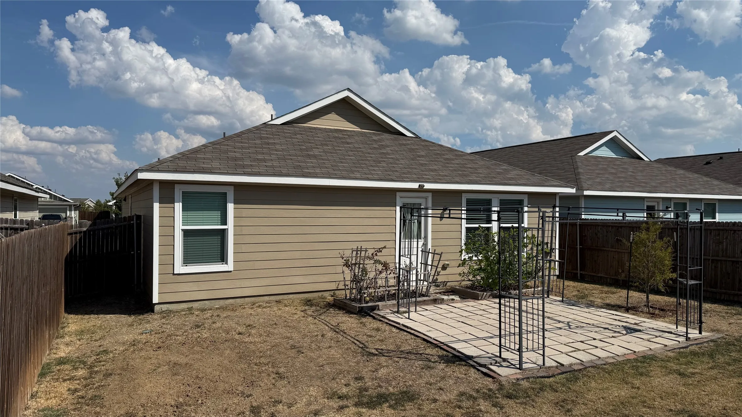 Rear exterior with tan siding and a dark shingle roof