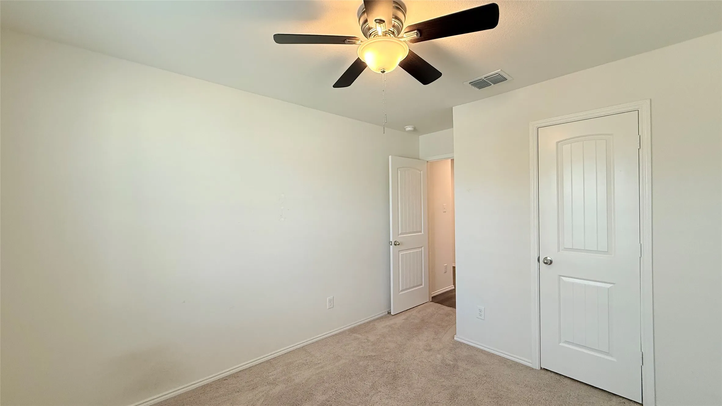 Neutral wall tones, ceiling fan with integrated lighting, and plush carpeting