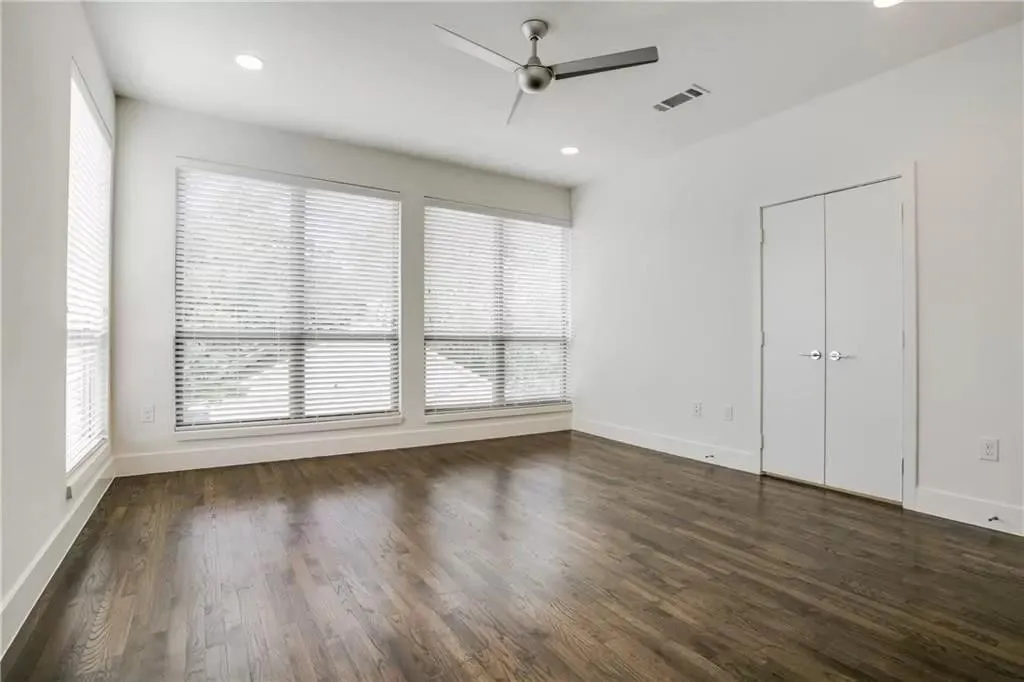 Wood-finish flooring with white trim, multiple windows with blinds, built-in ceiling lighting, and a ceiling fan