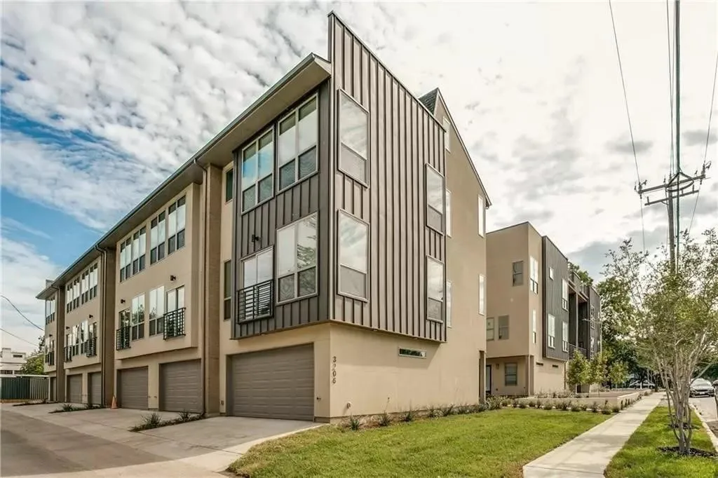 Contemporary multi-story facade featuring varied paneling, stucco siding, multiple large windows, and integrated two-car garages