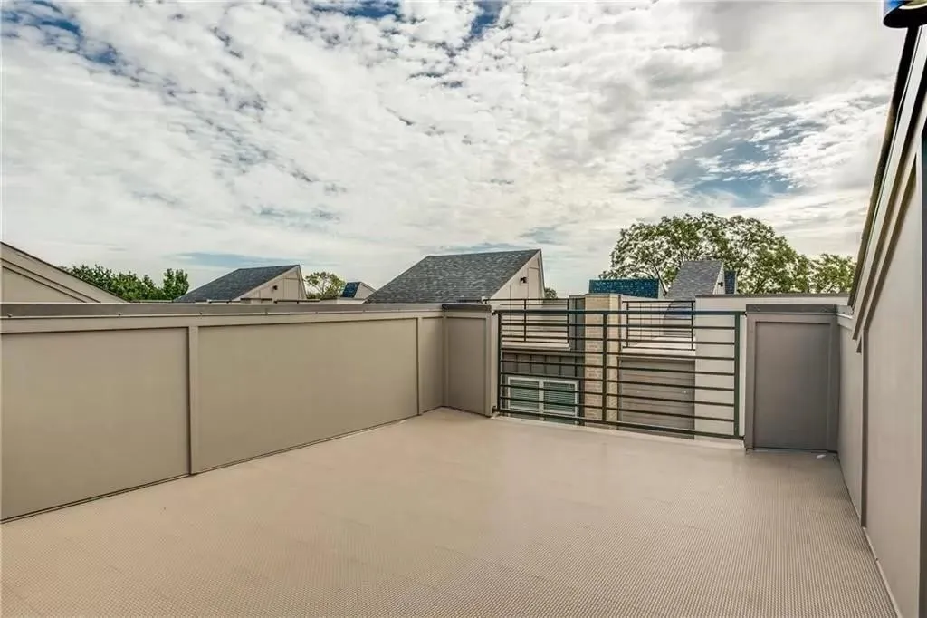 Rooftop patio with a textured surface, surrounded by privacy walls and a black metal railing