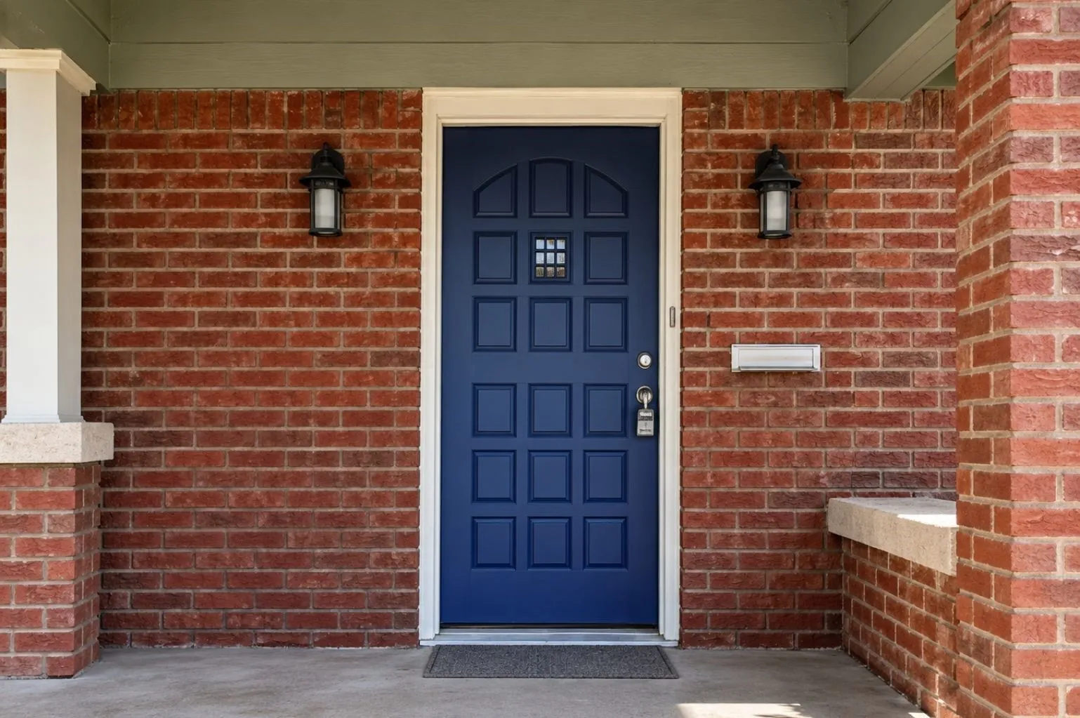Close-up porch perspective highlighting the navy-blue front door, red-brick exterior, white trim, porch lighting, and covered entry area.