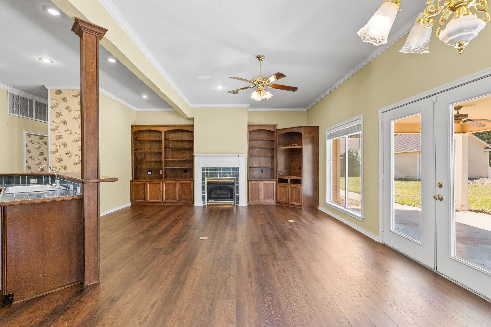 The great room off the kitchen has tiled fireplace, built-in bookcases, high beamed ceilings, and french doors to the back porch.