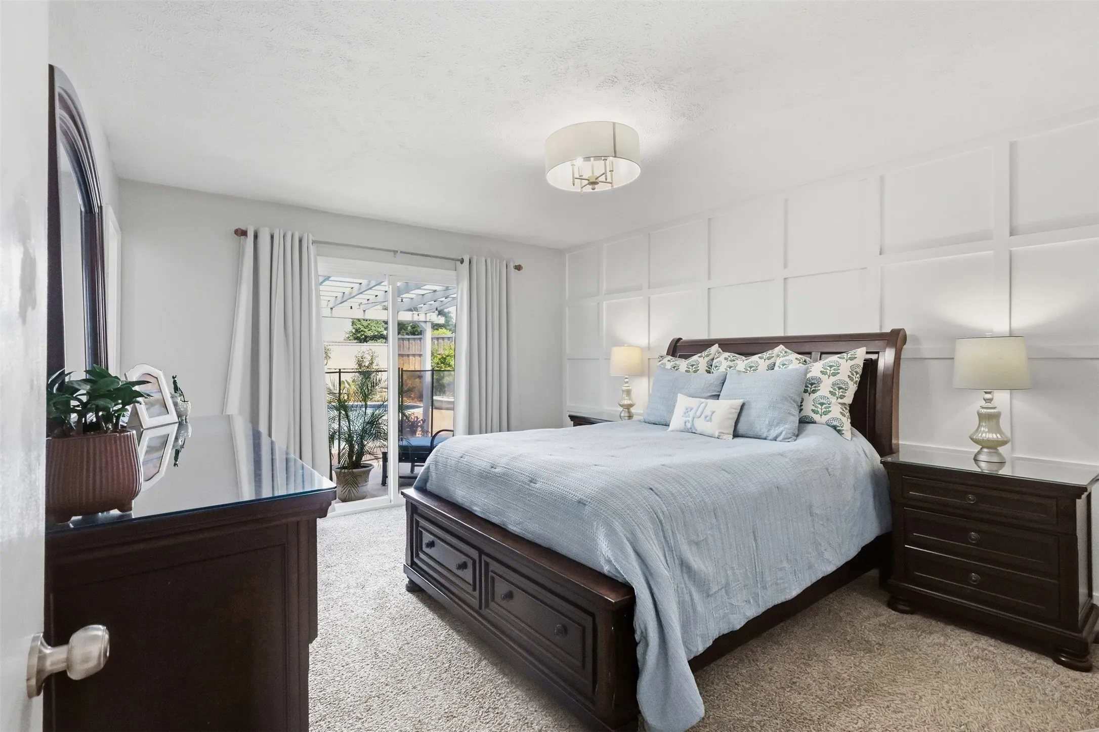 Spacious primary bedroom with soft natural light and a relaxing view toward the backyard and pool.