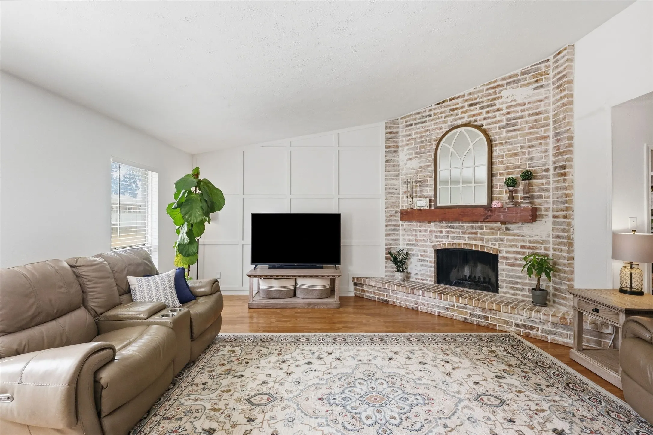 Spacious living room featuring abundant natural light, a cozy fireplace, and stylish accent details.