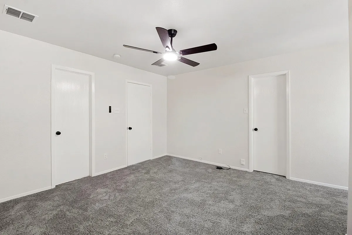Plush gray carpeting, crisp white walls, and a contemporary ceiling fan with integrated lighting