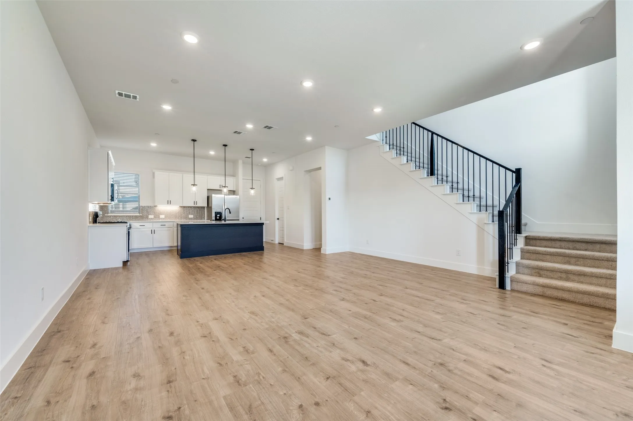 The open-concept design creates an effortless flow between the spacious living, dining, and kitchen areas, making the space ideal for both everyday living and entertaining. Engineered hardwood floors carry throughout, while recessed lighting and the expansive layout create a bright, modern, and cohesive feel.