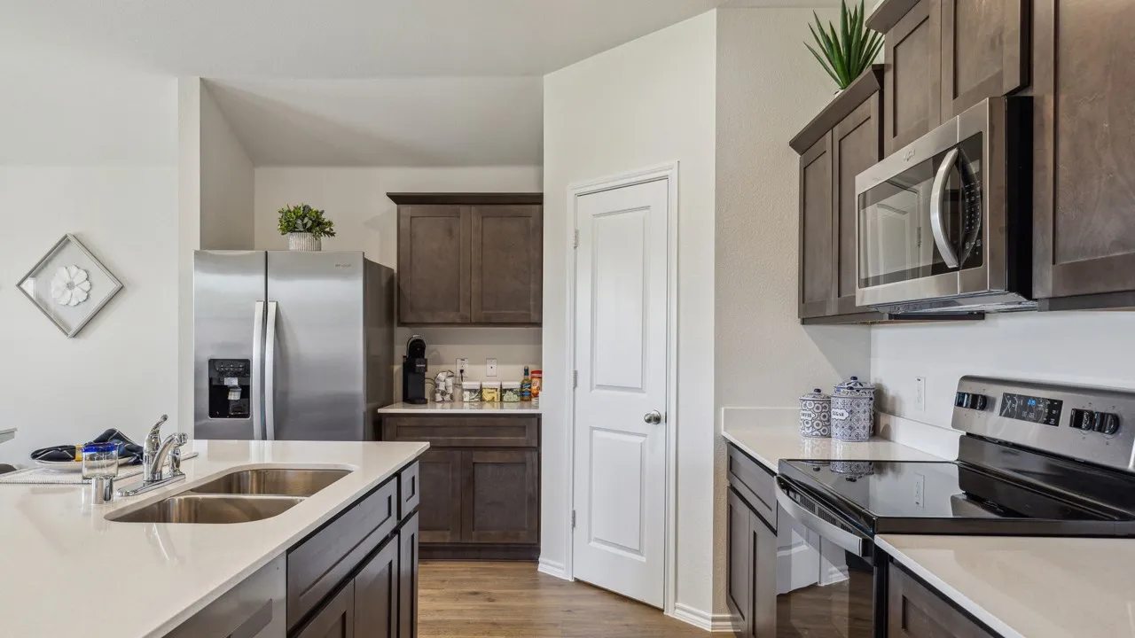 Kitchen with stainless steel appliances, dark wood finish cabinets, dark wood finished floors, and light stone countertops