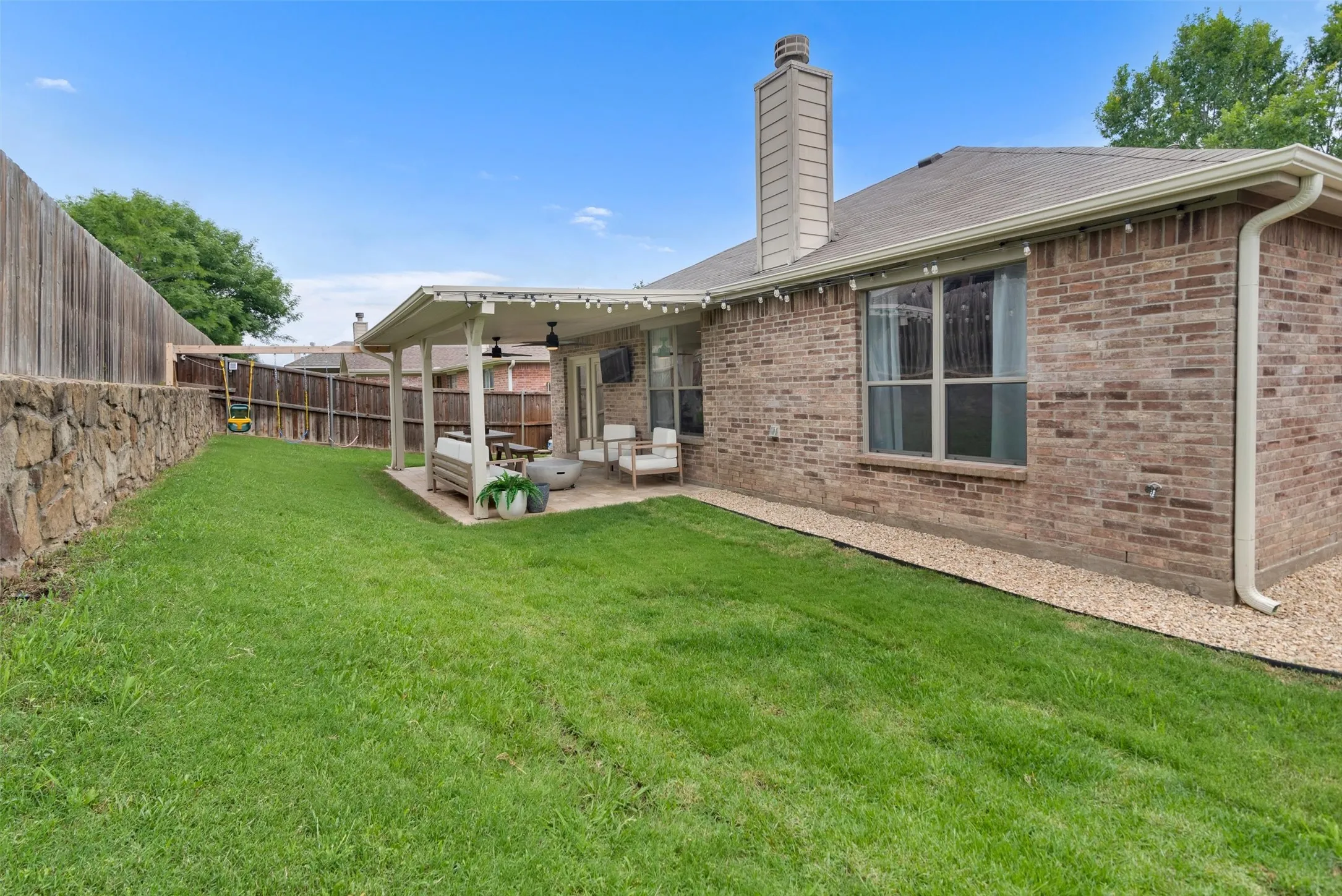 Expansive lawn area with a stone retaining wall and a wood privacy fence