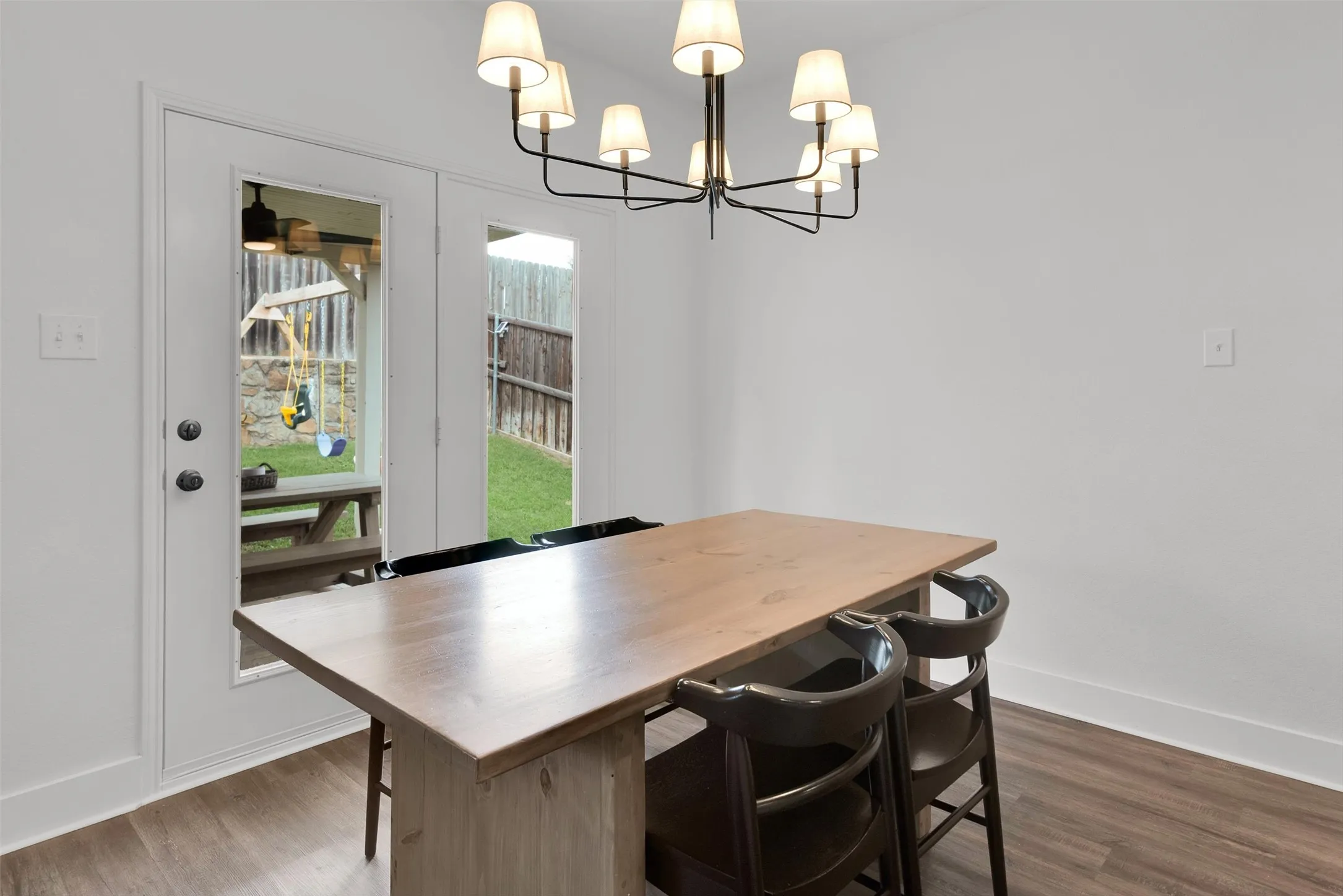 Wood-finish flooring, white walls, and a multi-arm chandelier